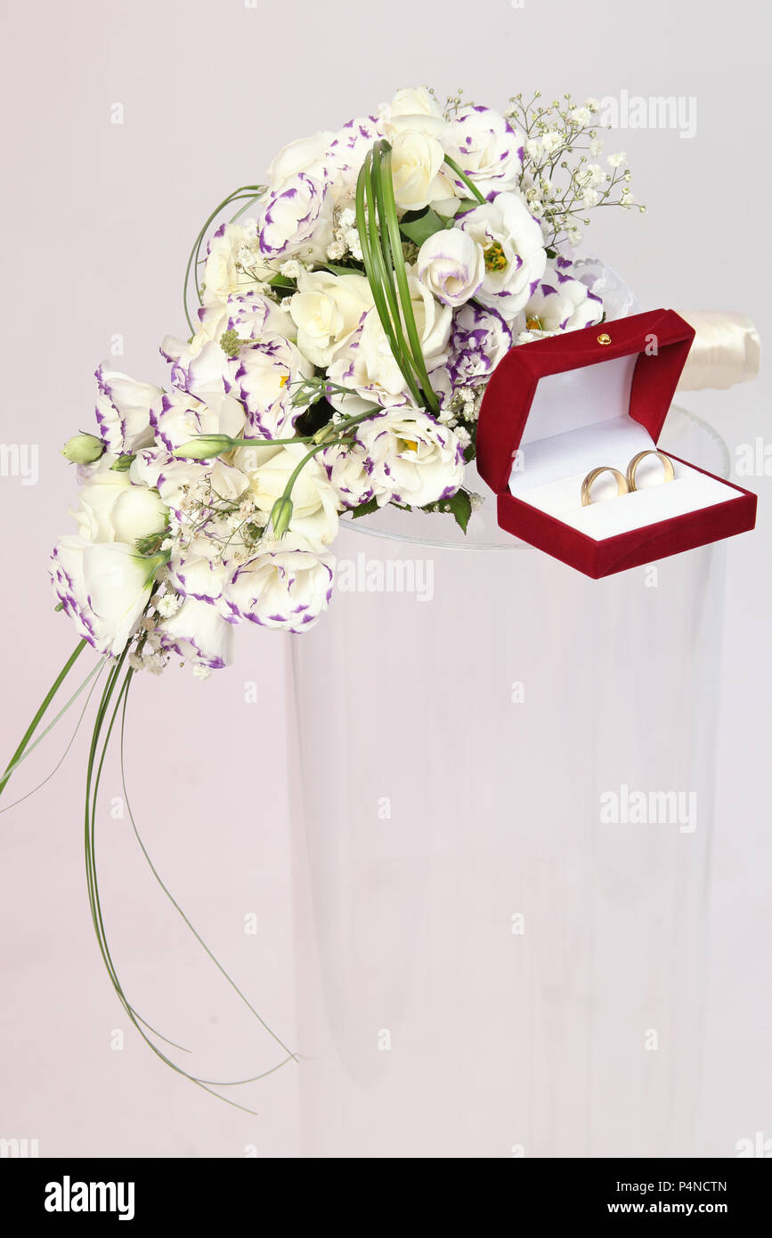 Wedding rings and bouquet on a pastel colour background. Studio shot. Stock Photo