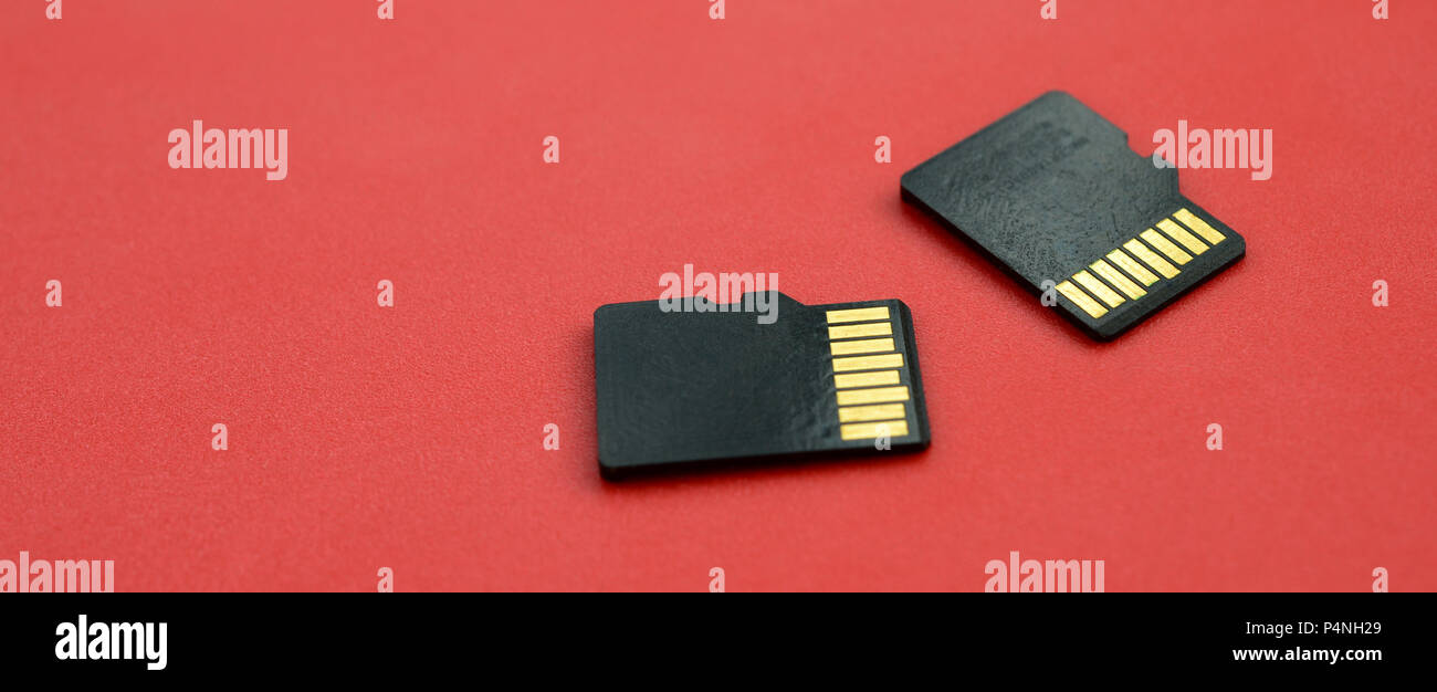 Two small micro SD memory cards lie on a red background. A small and compact data and information store . Stock Photo