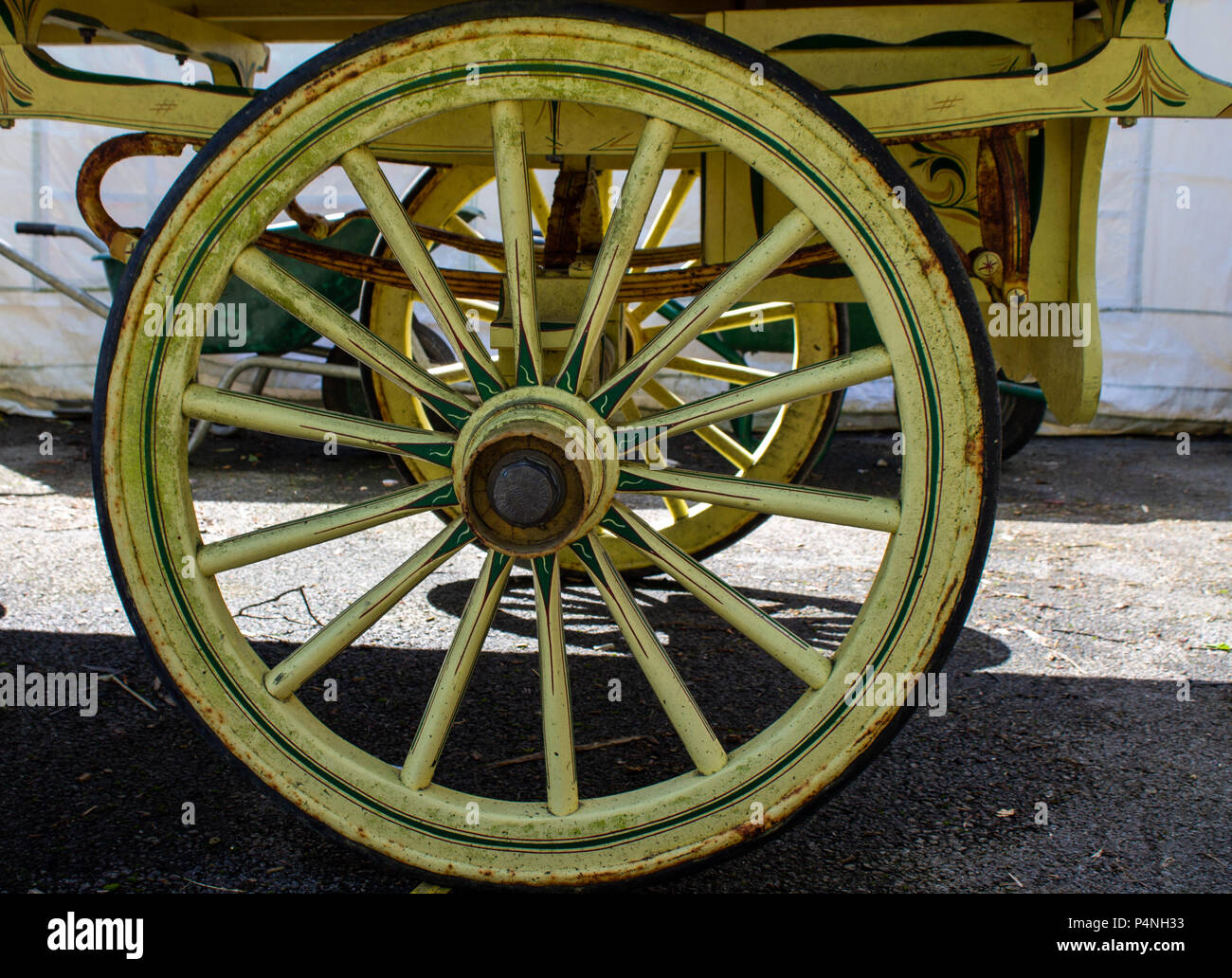 traditional wooden wheel on a gypsy caravan with ash spokes painted yellow and green. Stock Photo