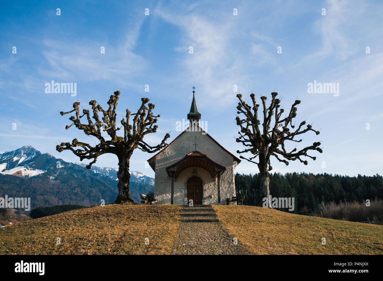 Small Swiss Chapel in Winter with Mountains in the Background Stock Photo