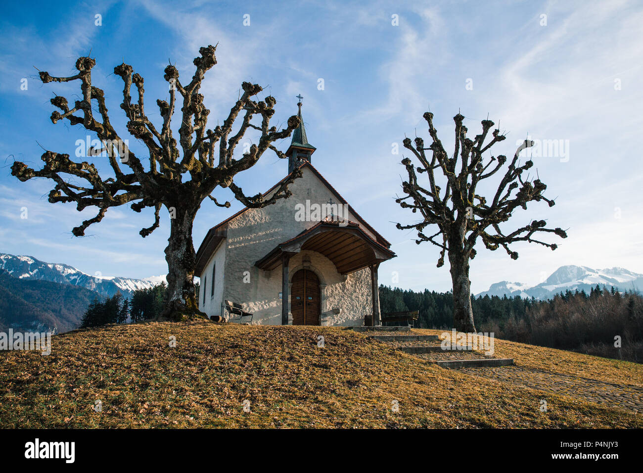 Small Swiss Chapel in Winter with Mountains in the Background Stock Photo