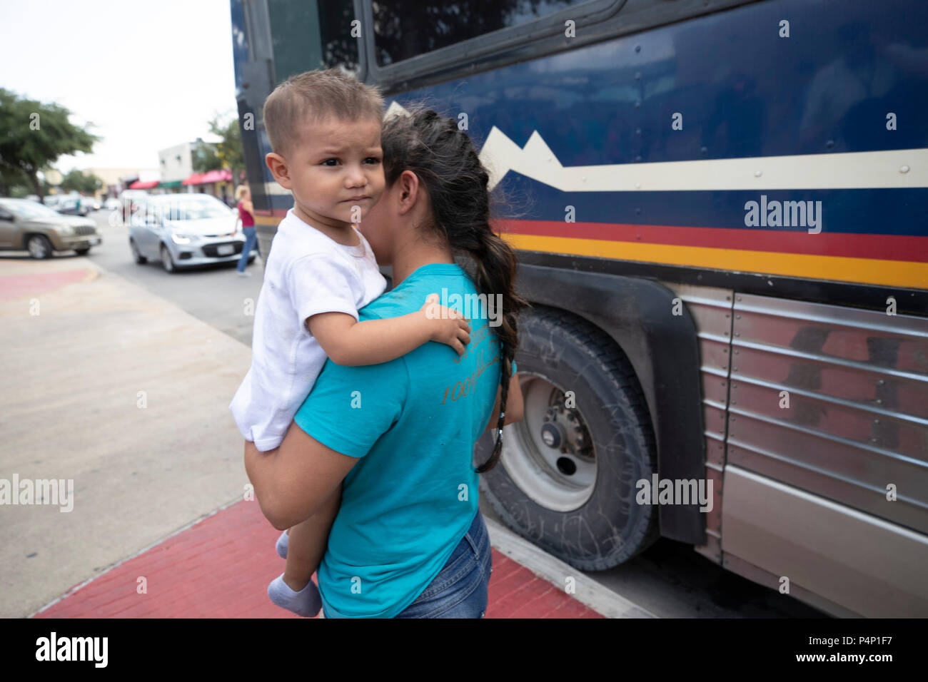 An immigrant mother, wearing an electronic monitoring device, and her young child captured coming across the United States-Mexico border in Texas are released at a bus station in McAllen. The family will travel to stay with family members in the U.S. while awaiting a  deportation or asylum hearing. Stock Photo