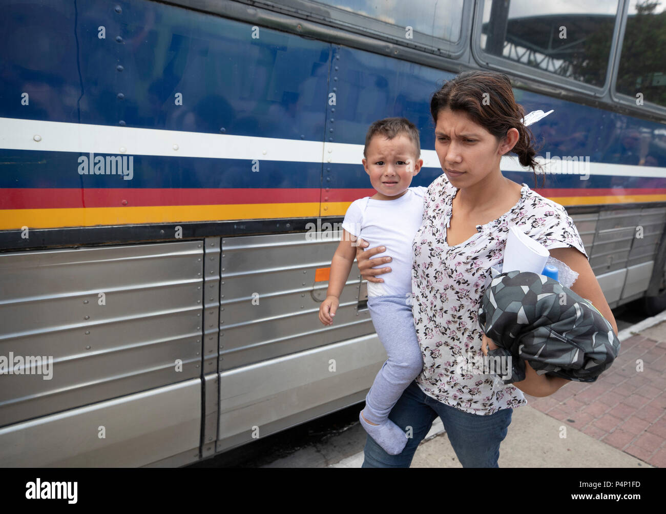 An immigrant mother, wearing an electronic monitoring device, and her young child captured coming across the United States-Mexico border in Texas are released at a bus station in McAllen. The family will travel to stay with family members in the U.S. while awaiting a  deportation or asylum hearing. Stock Photo