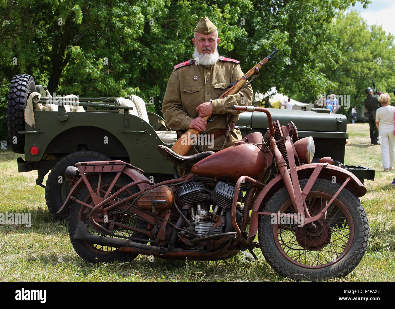 World War II Soviet Veteran wearing a old military uniform with authentic Harley Davidson motorcycle, Mosin's three-line rifle, WillysMB Stock Photo