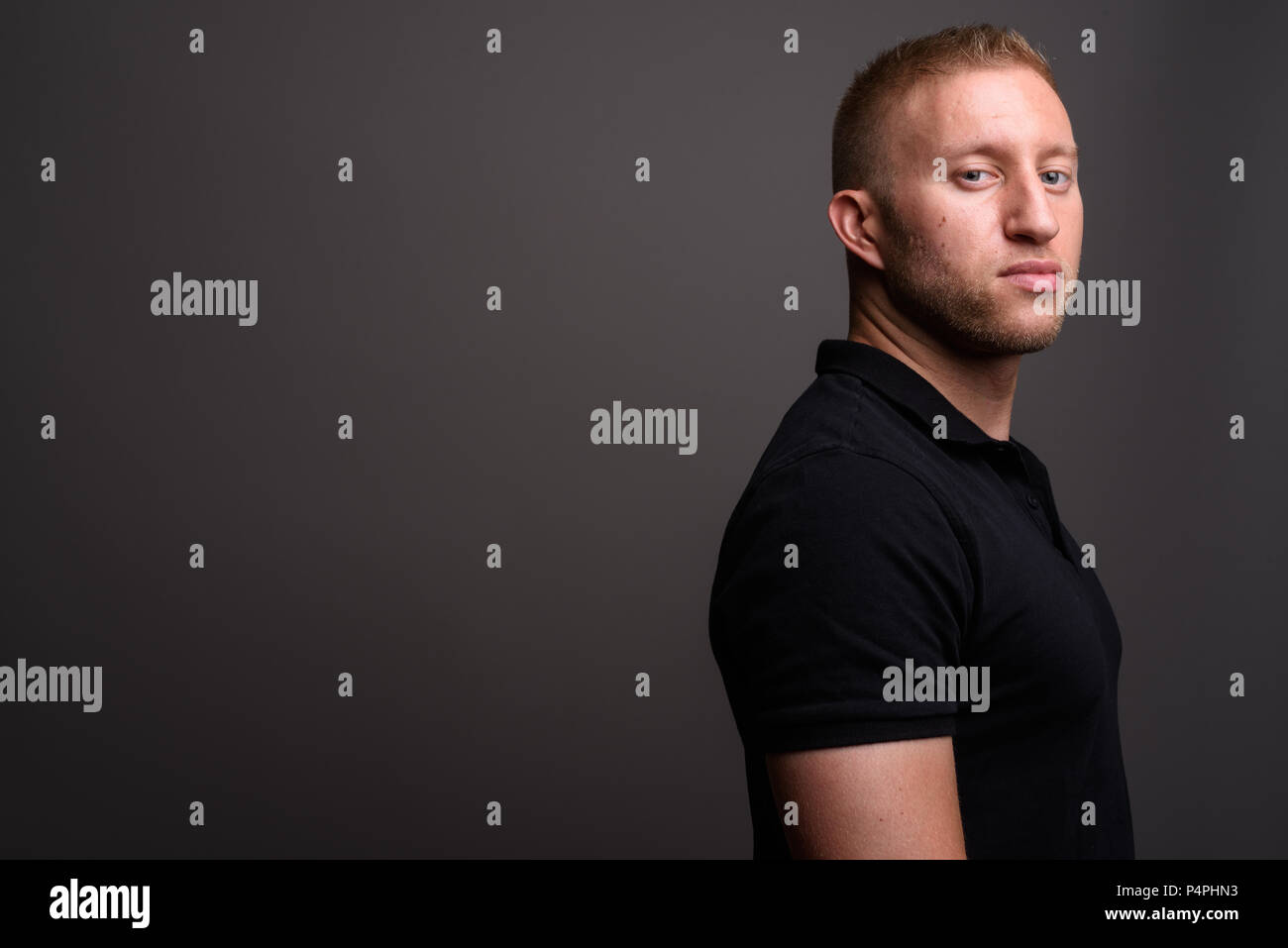 Man with blond hair wearing black polo shirt against gray backgr Stock Photo