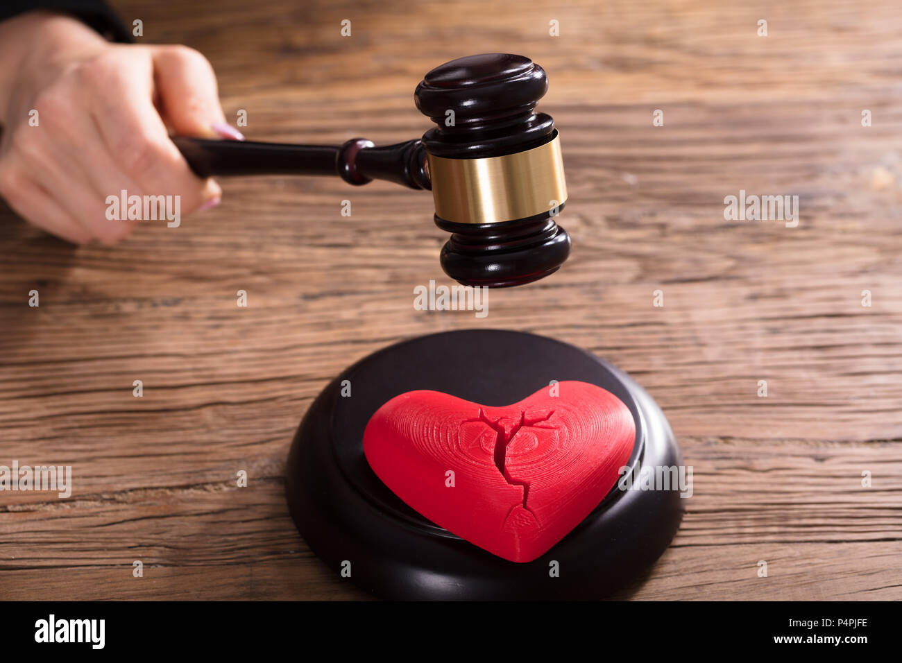 Close-up Of A Broken Red Heart In Front Of Judge Striking Mallet Stock Photo