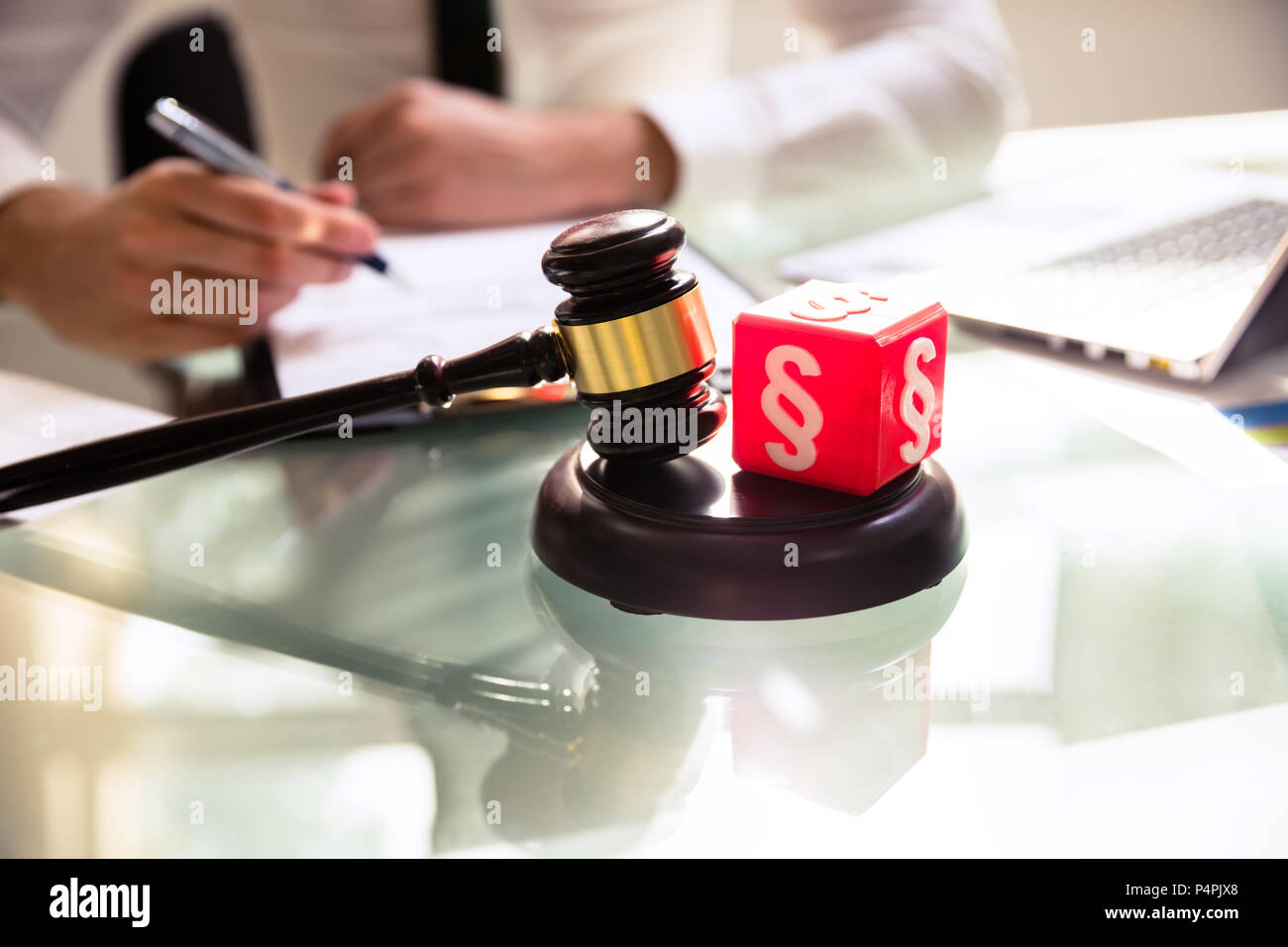 Red Cubic Block With Paragraph Symbol And Gavel On Reflective Desk Stock Photo