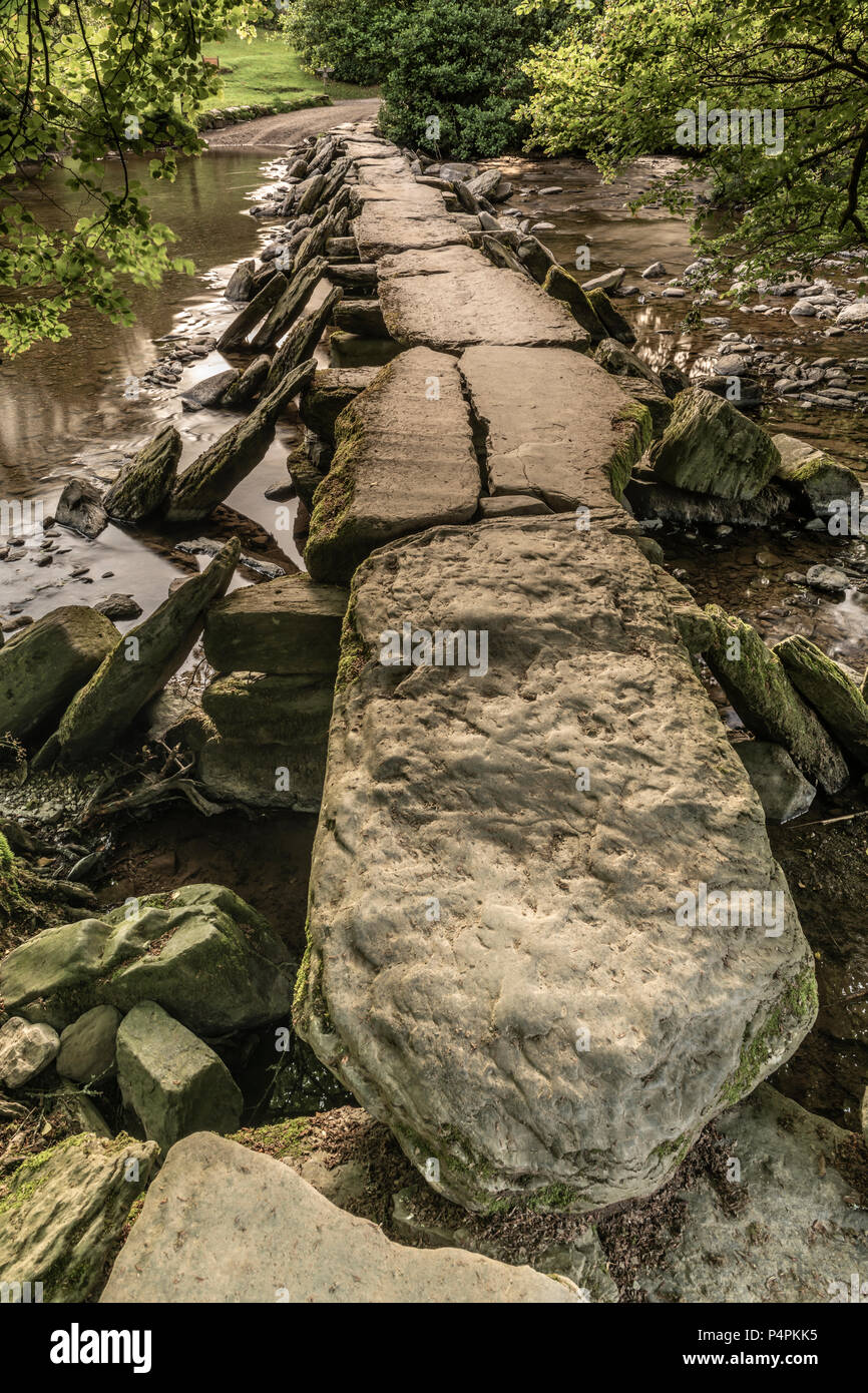 UK Weather -June 21st, the longest day, the wind strengthens at dawn clearing the cloud allowing the sun to light up the historic Tarr Steps on the Ri Stock Photo