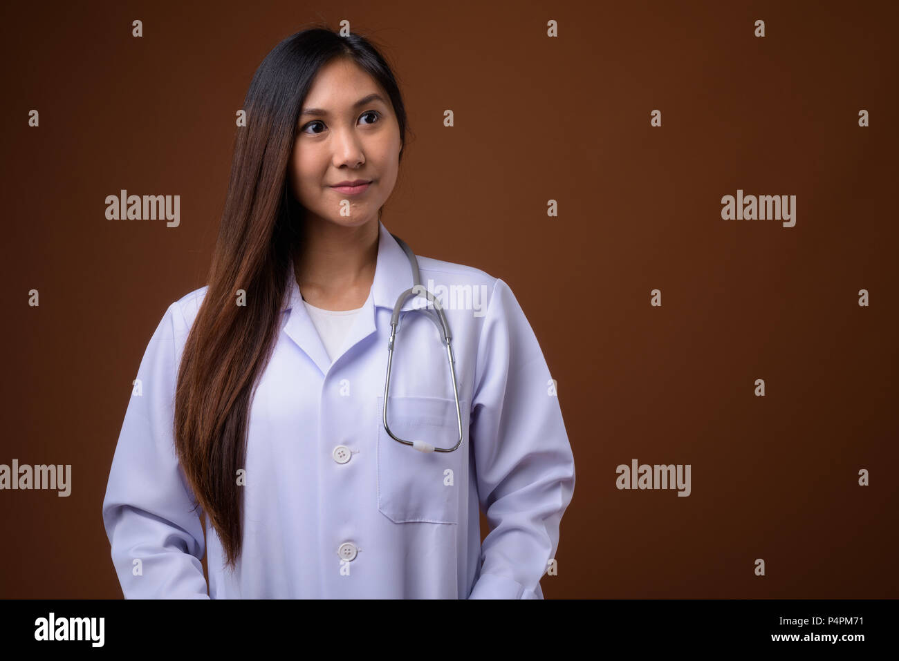 Young beautiful Asian woman doctor against brown background Stock Photo ...