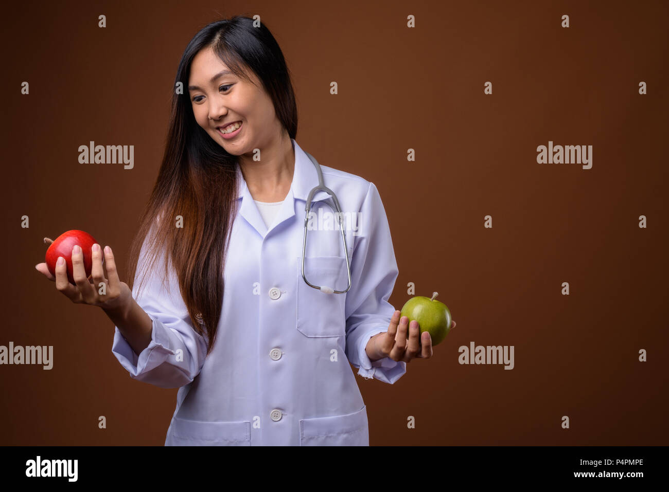 Young beautiful Asian woman doctor against brown background Stock Photo ...