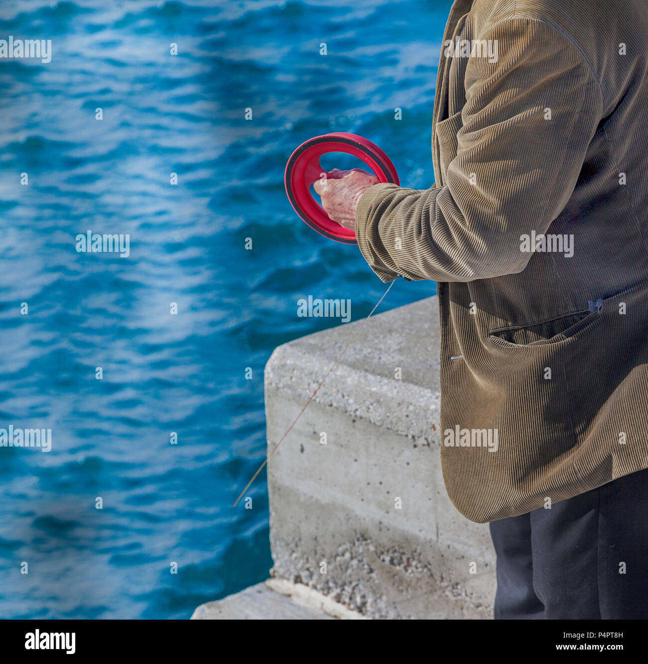 Man fishing. Senior adult male fishing standing up with a nylon reel in the Mediterranean Sea. Stock Image. Stock Photo