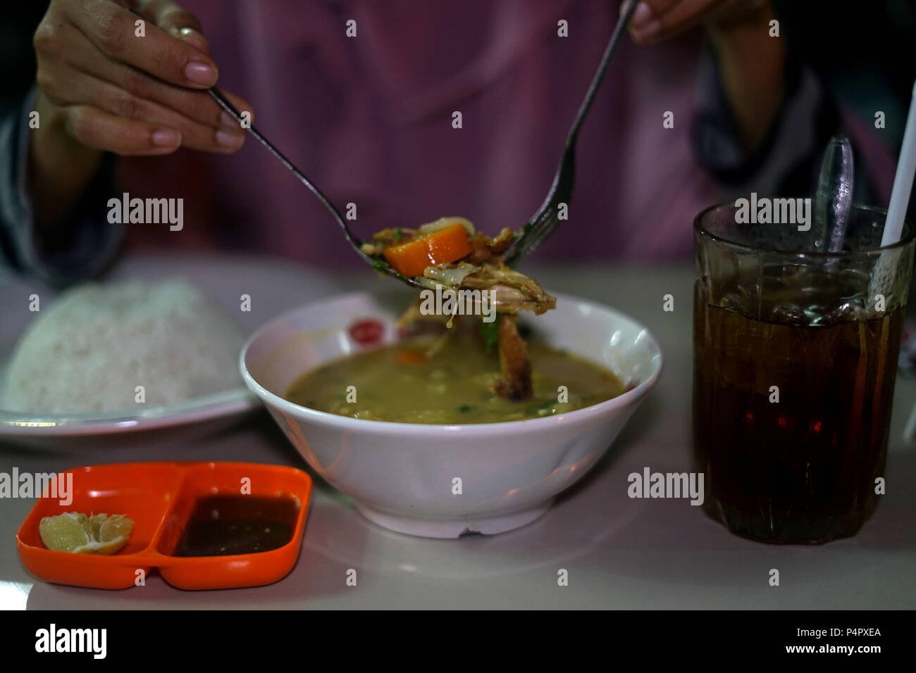 Delicious Nasi Soto, the Traditional Indonesian Food Served with Rice and Ice Tea Stock Photo