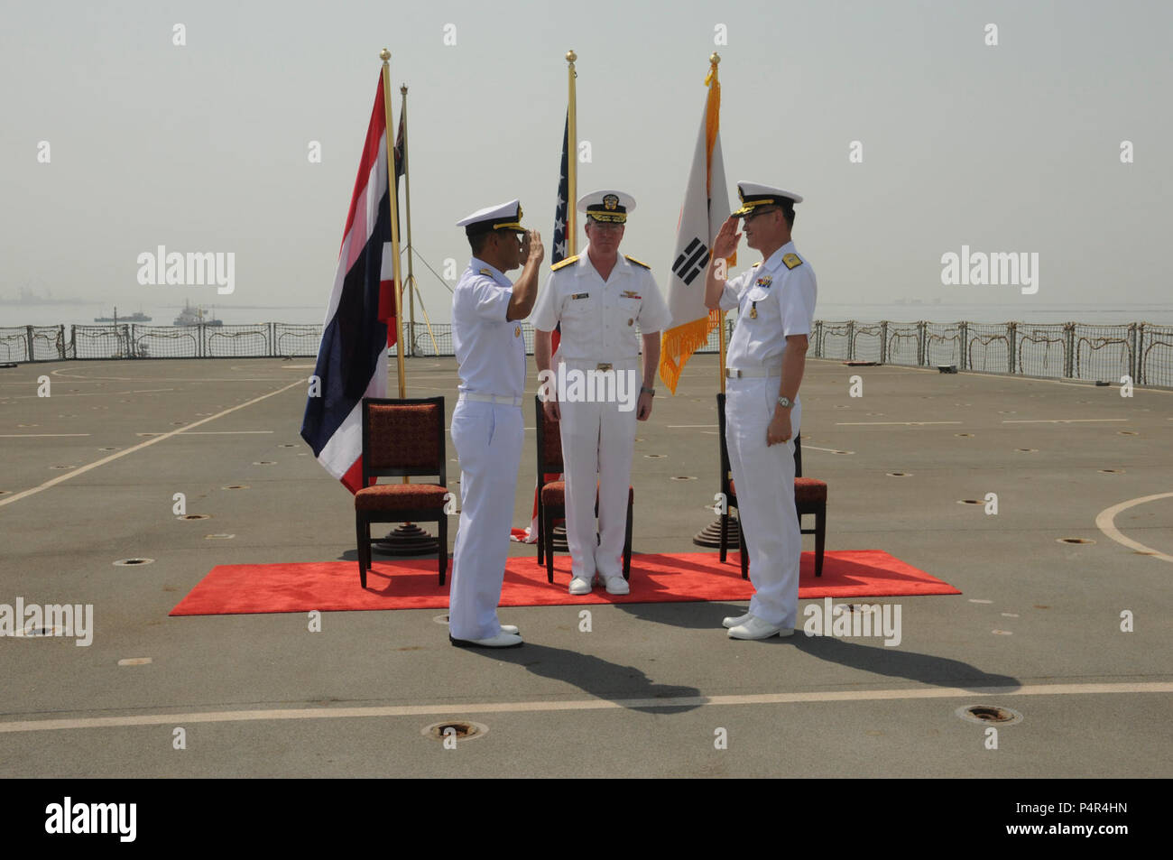 MINA SALMAN PIER, Bahrain (June 18, 2012) Republic of Korea Navy Rear Adm. Anho Chung, relieves, Royal Thai Navy Rear Adm. Tanin Likitawong, commander, Combined Task Force (CTF) 151 while Vice Adm. John. Miller, commander, U.S. Naval Forces Central Command/Fifth Fleet/Combined Maritime Forces, center, observes, during change of command ceremony aboard Royal Fleet Auxiliary (RFA) Fort Victoria (A387). CTF 151 is a multi-national, mission-based task force working under CMF, to conduct counter-piracy operations in the Southern Red Sea, Gulf of Aden, Somali Basin, Arabian Sea, and Indian Ocean. Stock Photo