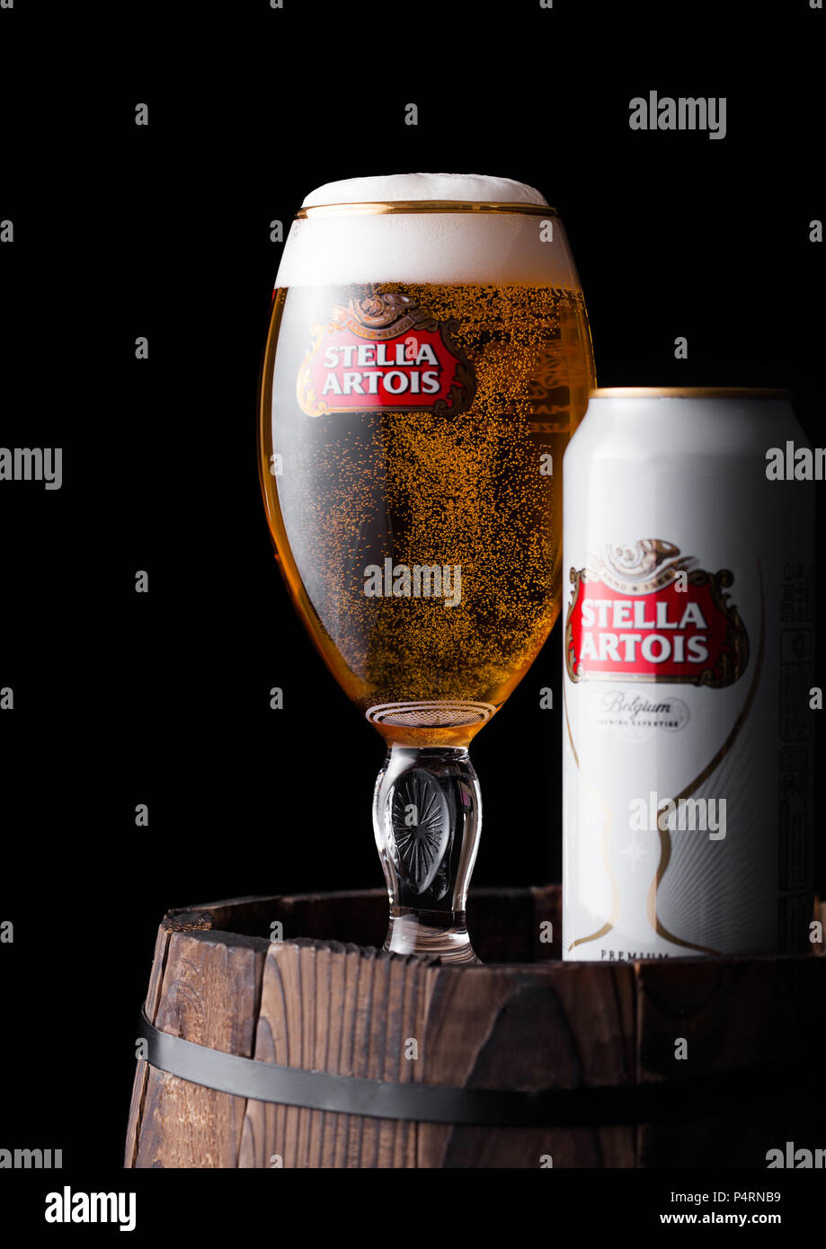 LONDON, UK - JUNE 06, 2018: Cold glass and aluminium can of Stella Artois beer on old wooden barrel on black background. Stock Photo