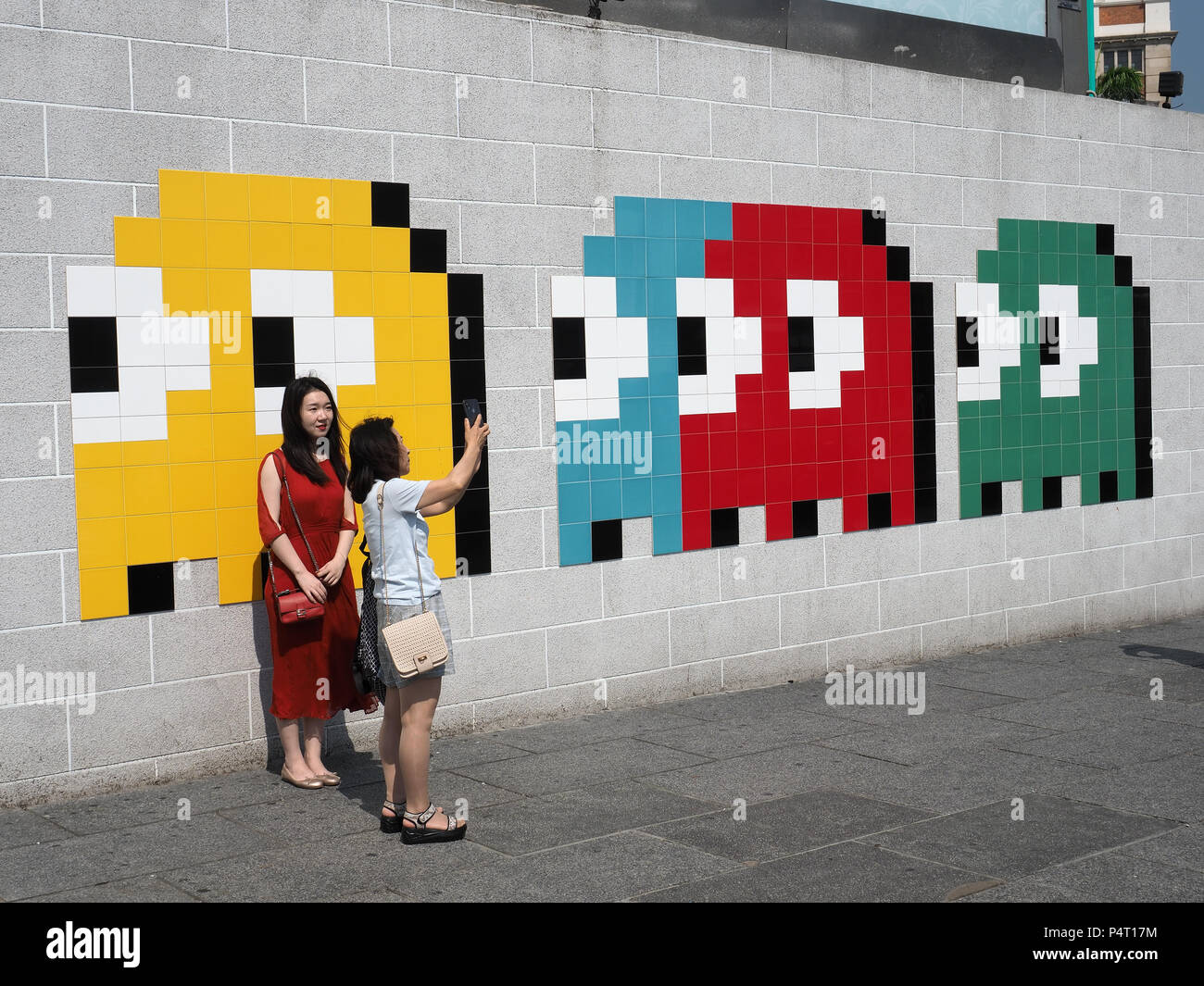 View of tourists taking a selfie in front of a mosaic artwork by the French undercover artist Invader in Hong Kong Stock Photo