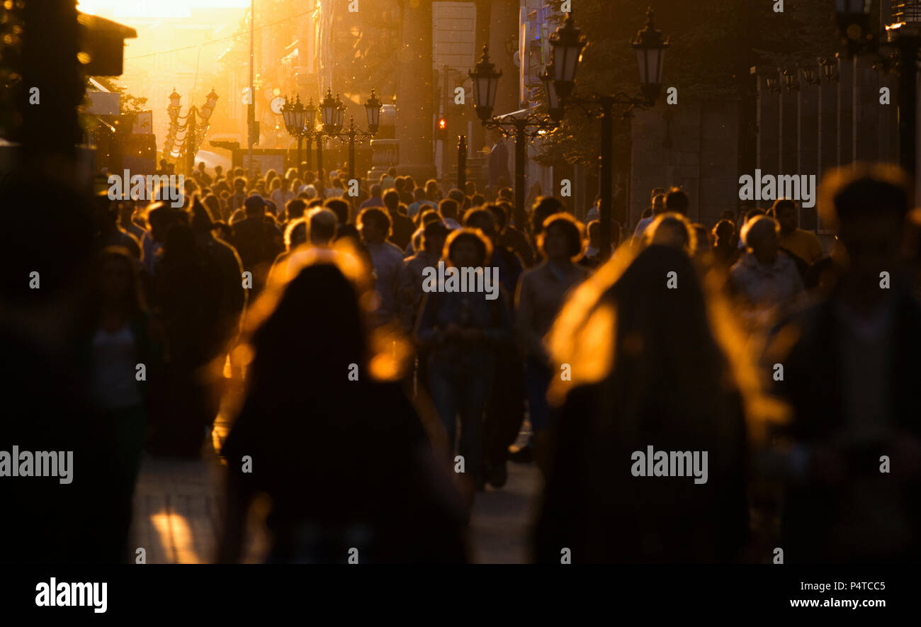 Silhouettes of people crowd walking down the street at summer evening ...