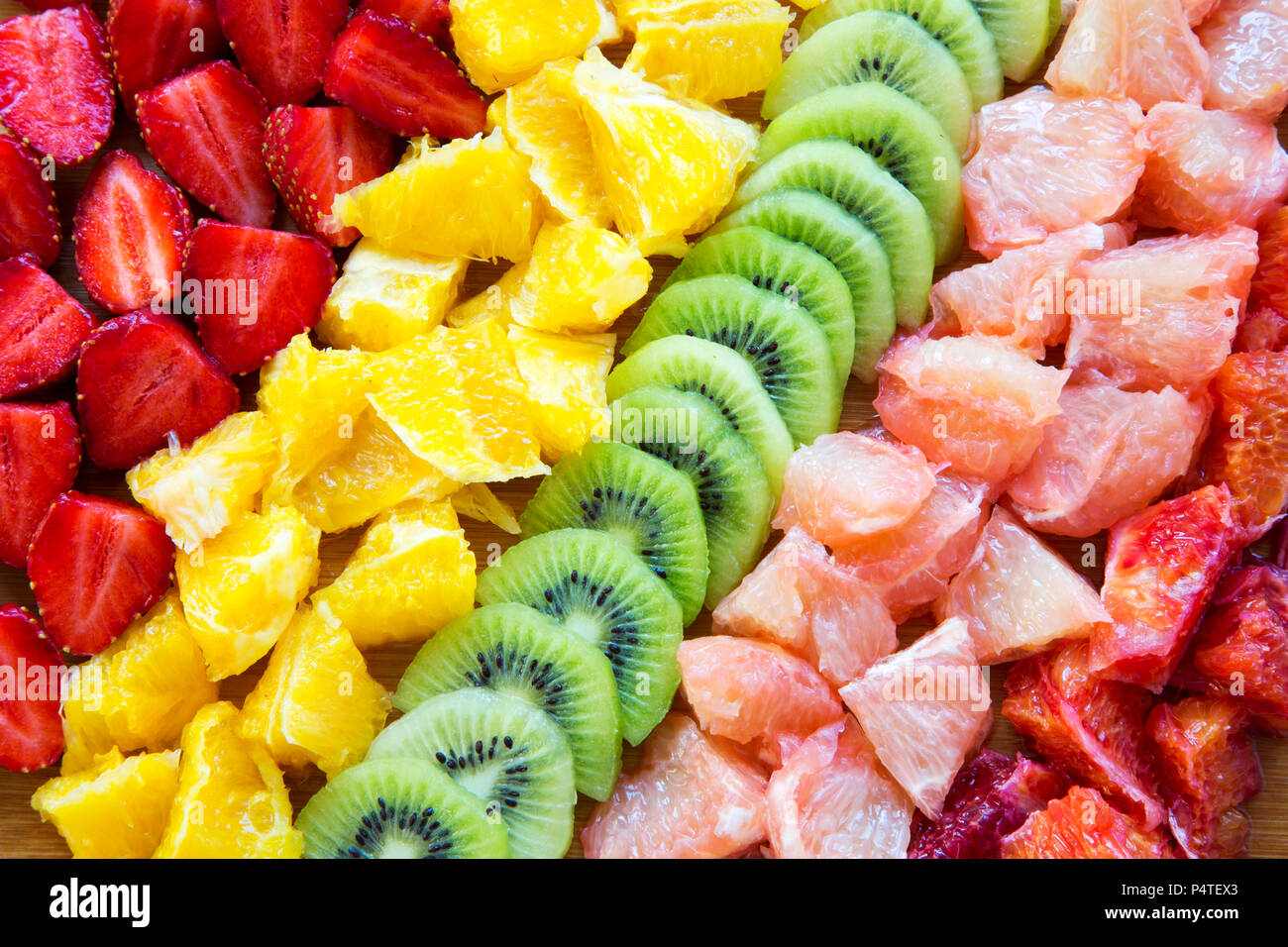 Chopped fresh raw colorful fruits arranged on cutting board, closeup