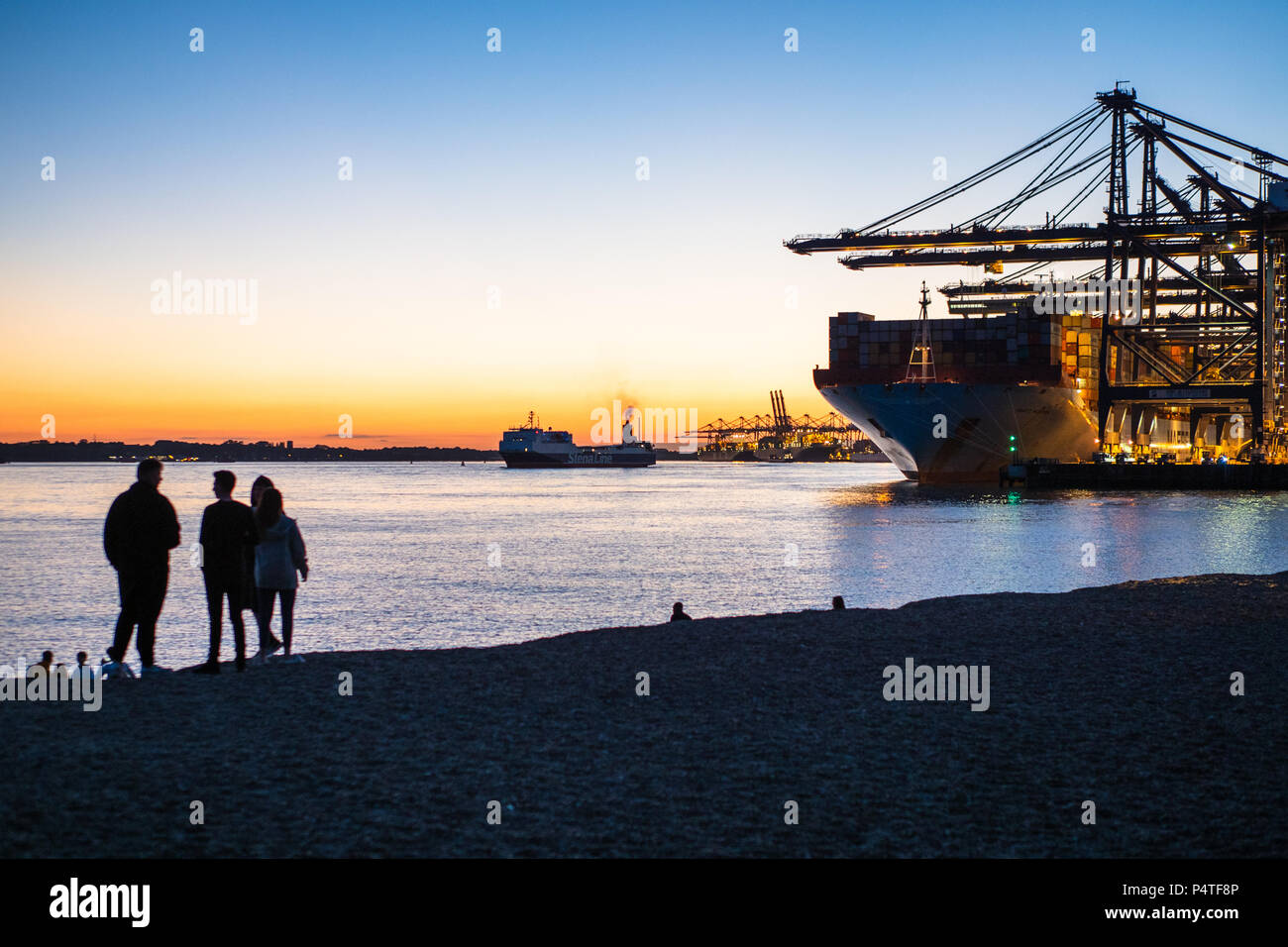 Global Britain Port of Felixstowe - young people view ships loading and unloading containers at dusk in Felixstowe Port, UK's largest container port. Stock Photo