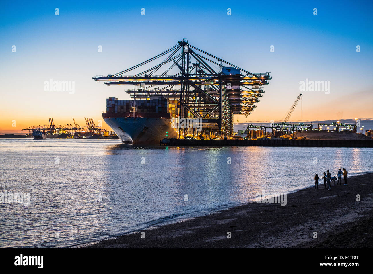 Port of Felixstowe - young people view ships loading and unloading containers at dusk in Felixstowe Port, the UK's largest container port. Stock Photo