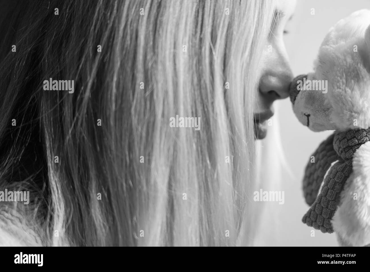 portrait of a girl with a soft toy bear nose to nose Stock Photo