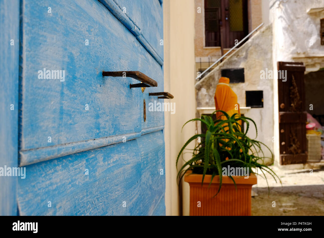 Old and aged historic door in blue wood in the city of San Felice Circeo (seaside), Lazio, Italy - dress for sale in the background. Stock Photo