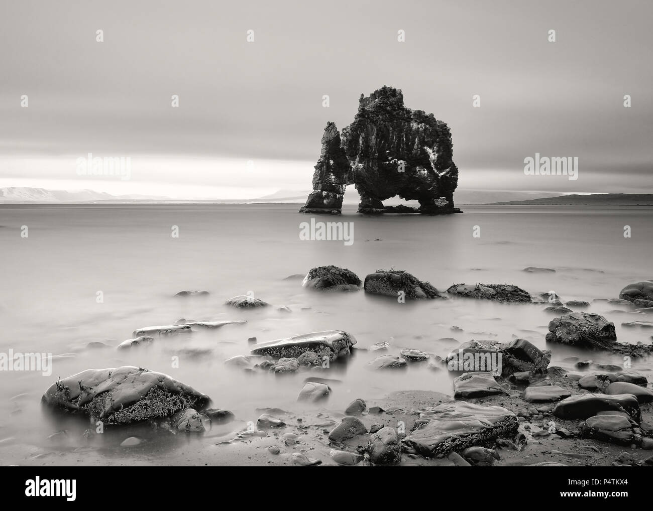 Scenic view of a striking rock formation in shallow water on a beach with stones - Location: Iceland, east coast of the Vatnsnes peninsula in the nort Stock Photo