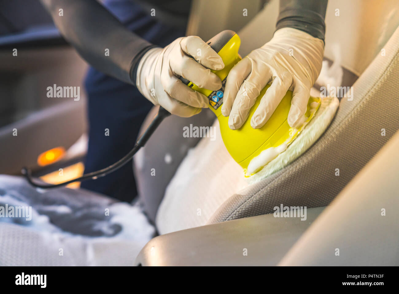 a man cleaning car interior by use foam chemical  and scrubbing machine. Stock Photo