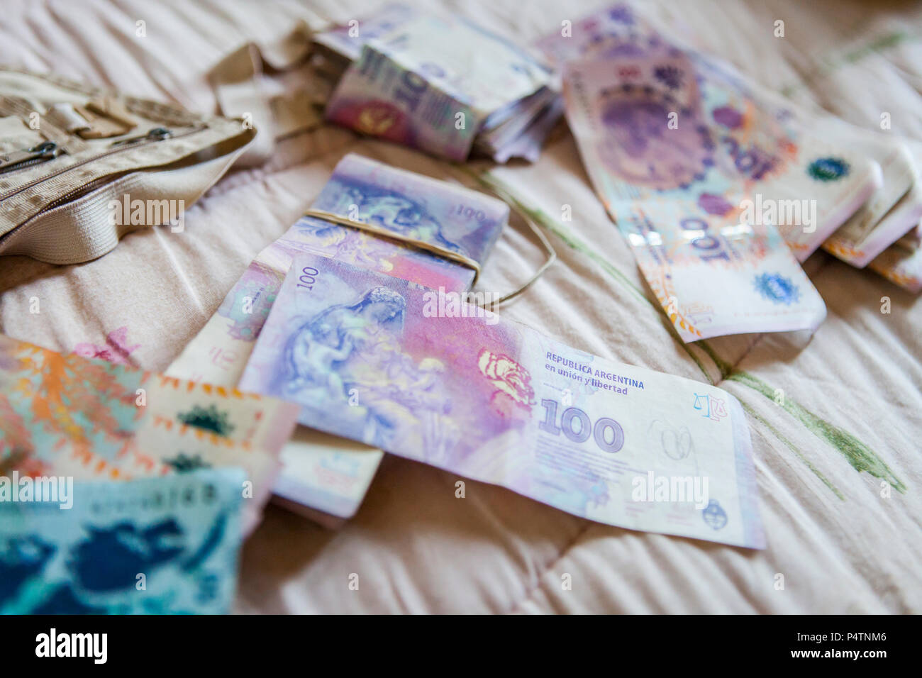 Foreign money, Argentinian pesos, spreaded out on a hotel room bed Stock Photo