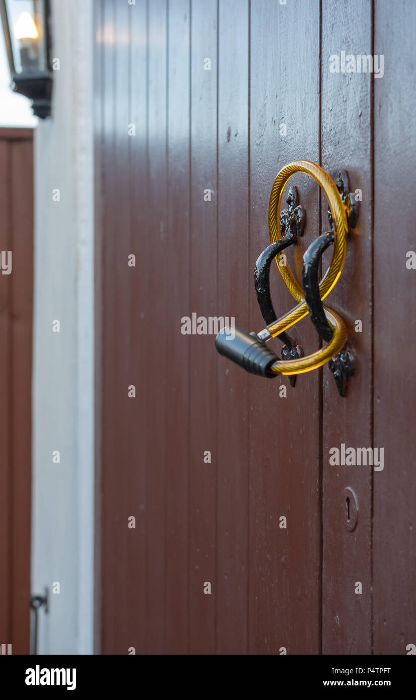 Shallow focus of a generic steel-wire bicycle antitheft device seen looped through the handles of a double door garage. Stock Photo