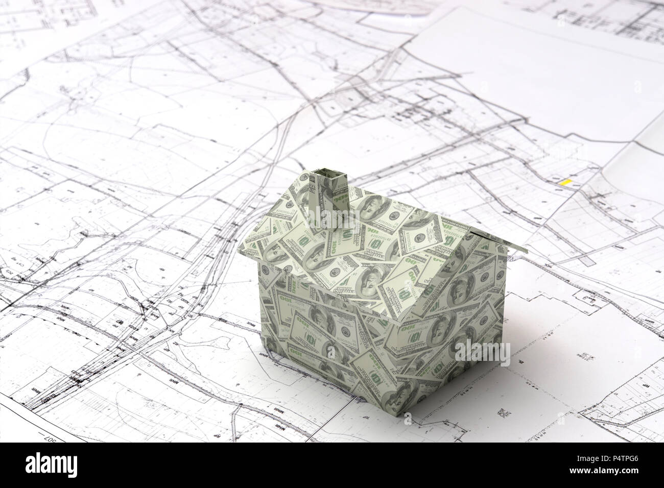 Little 3D cardboard house model wrapped around with American dollar bills on building plan Stock Photo