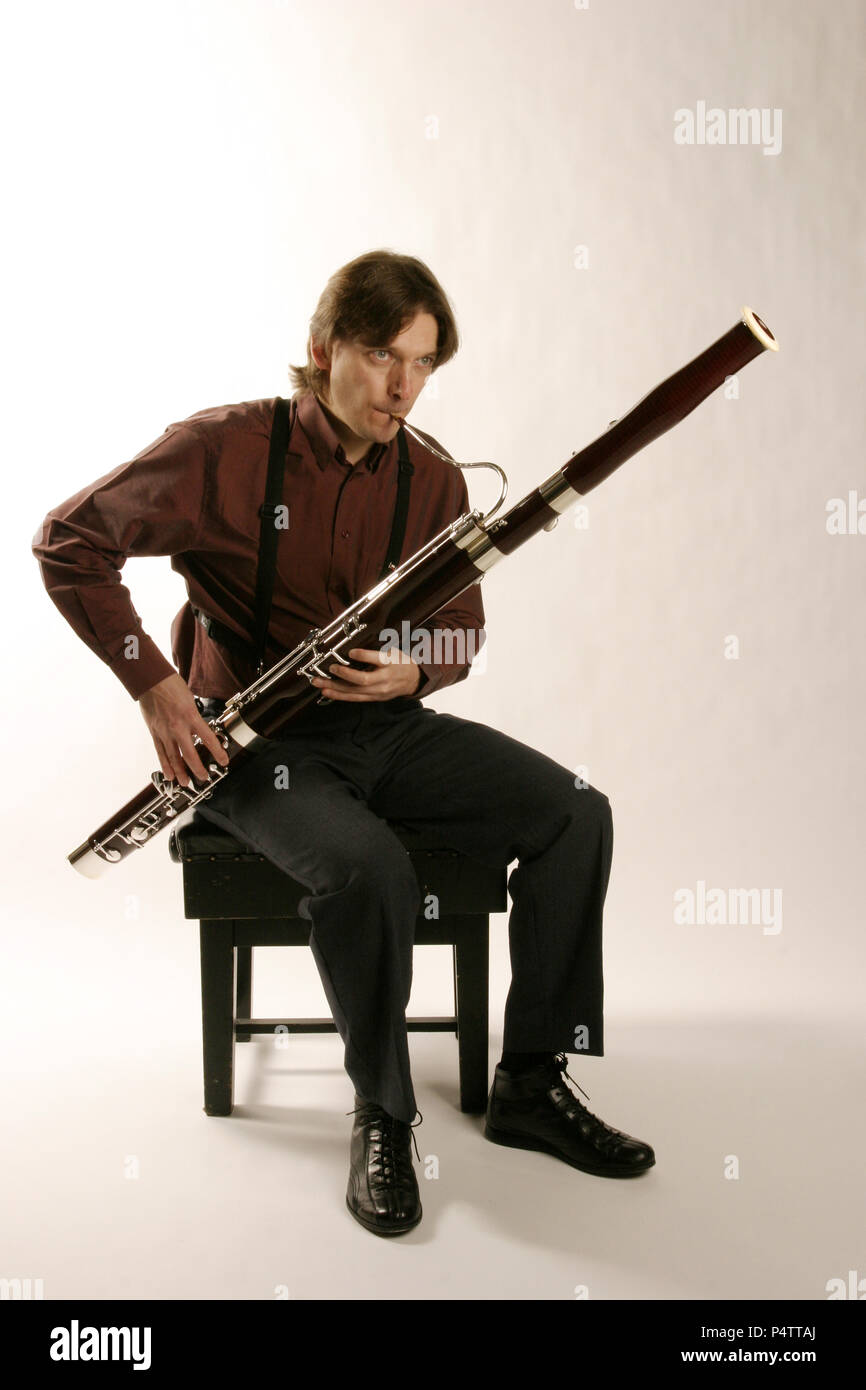 Bassoonist in playing position, using a body strap to support the