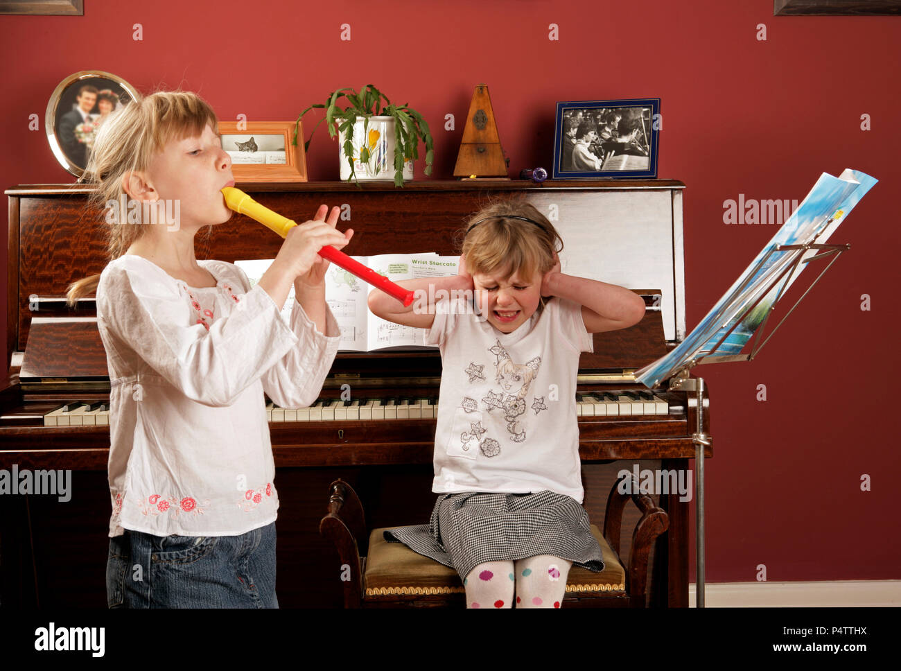 one girl playing the recorder, the other showing her appreciation. Stock Photo