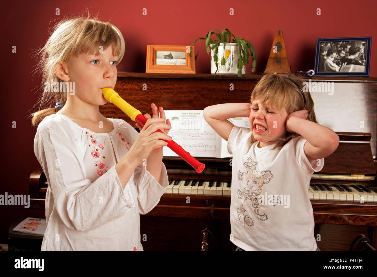 Young girl playing the recorder, whilst the other shows her appreciation Stock Photo