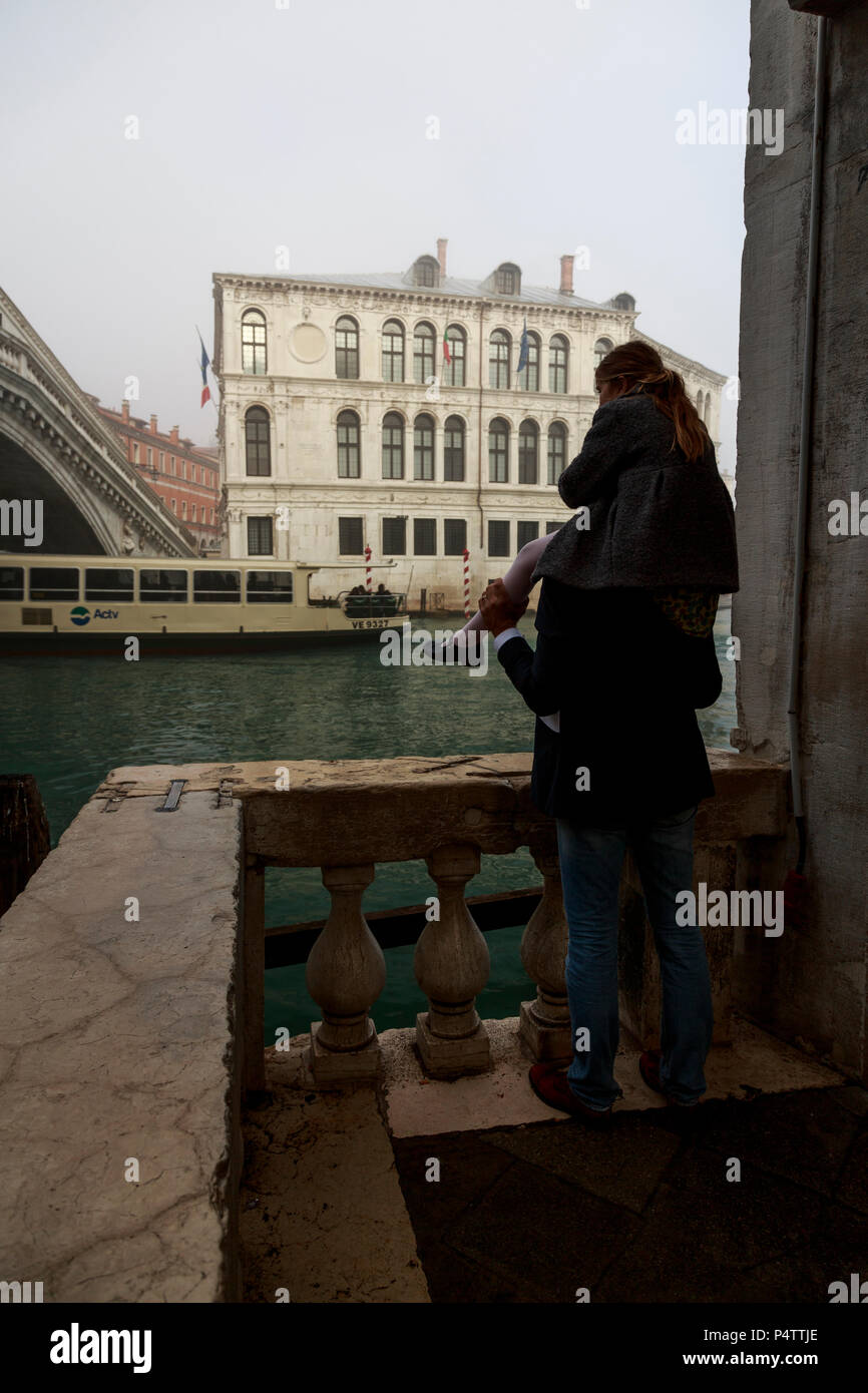 Father and young daughter watching Grand Canal on hazy early morning, Rialto, Venice, Italy. Stock Photo
