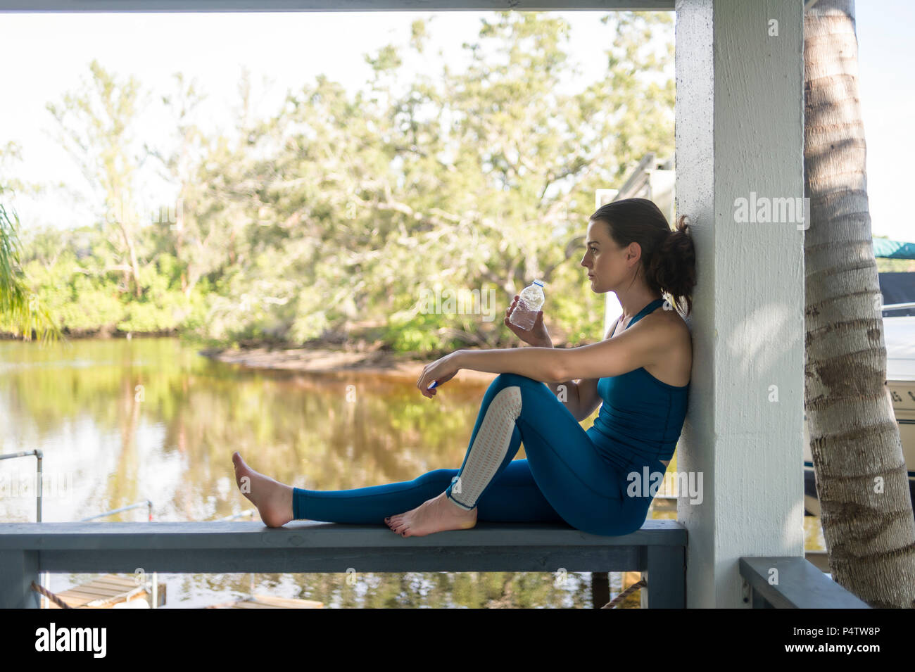 woman sitting resting and drinking water after exercise Stock Photo