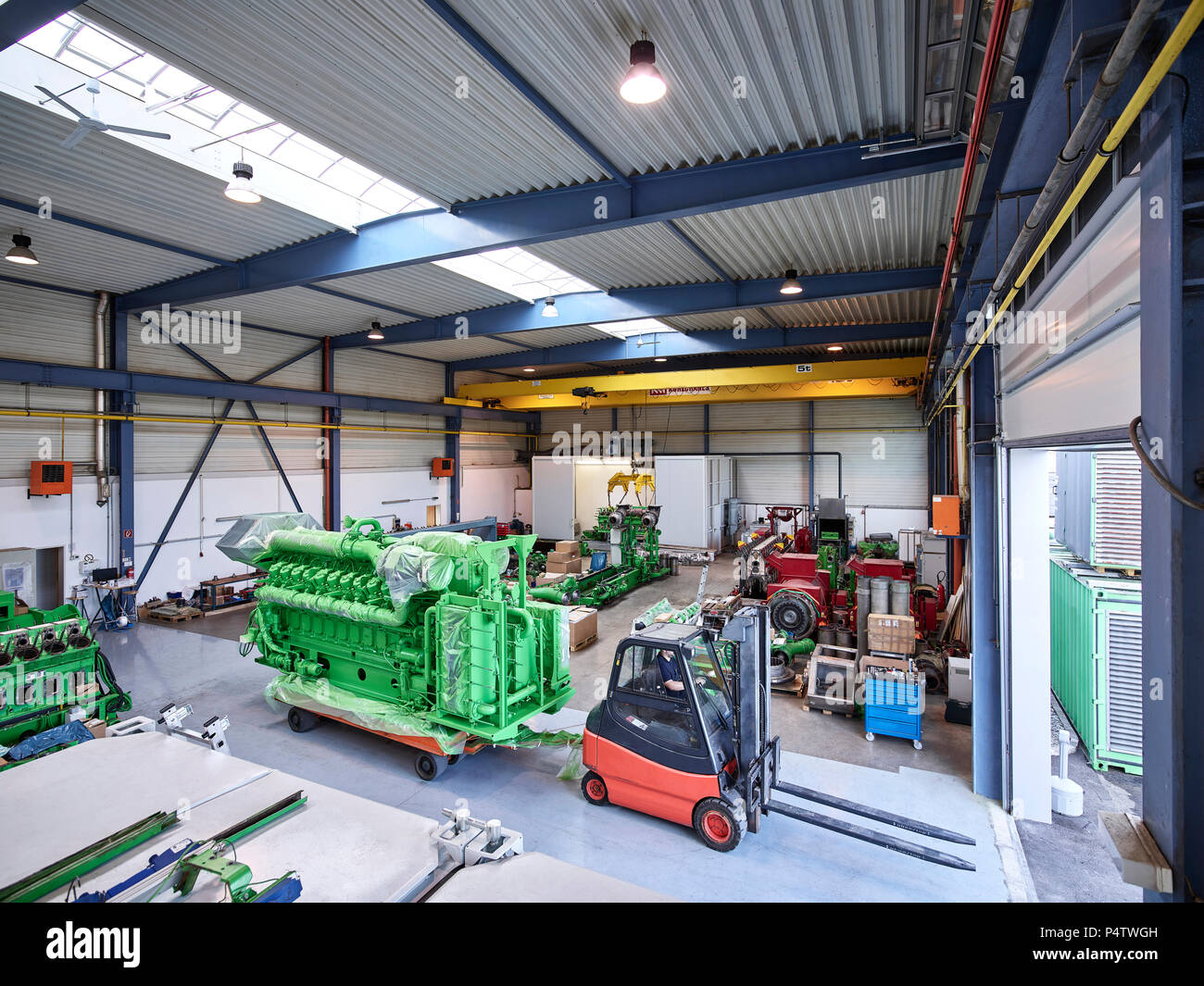 Fork-lift driver pulling gas engine out of factory shop floor Stock Photo
