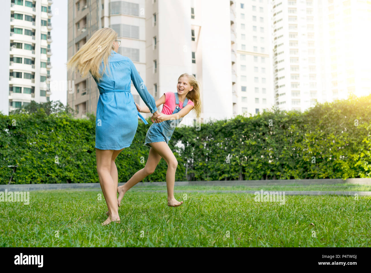 Happy mother and daughter having fun in urban city garden Stock Photo