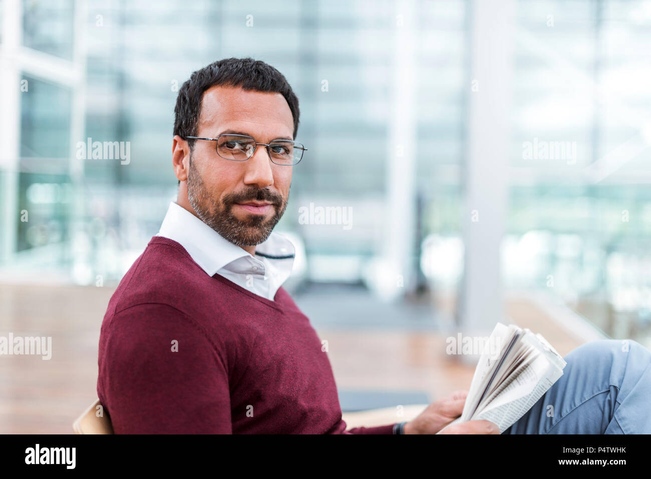 Businessman reading a newspaper in waiting hall Stock Photo