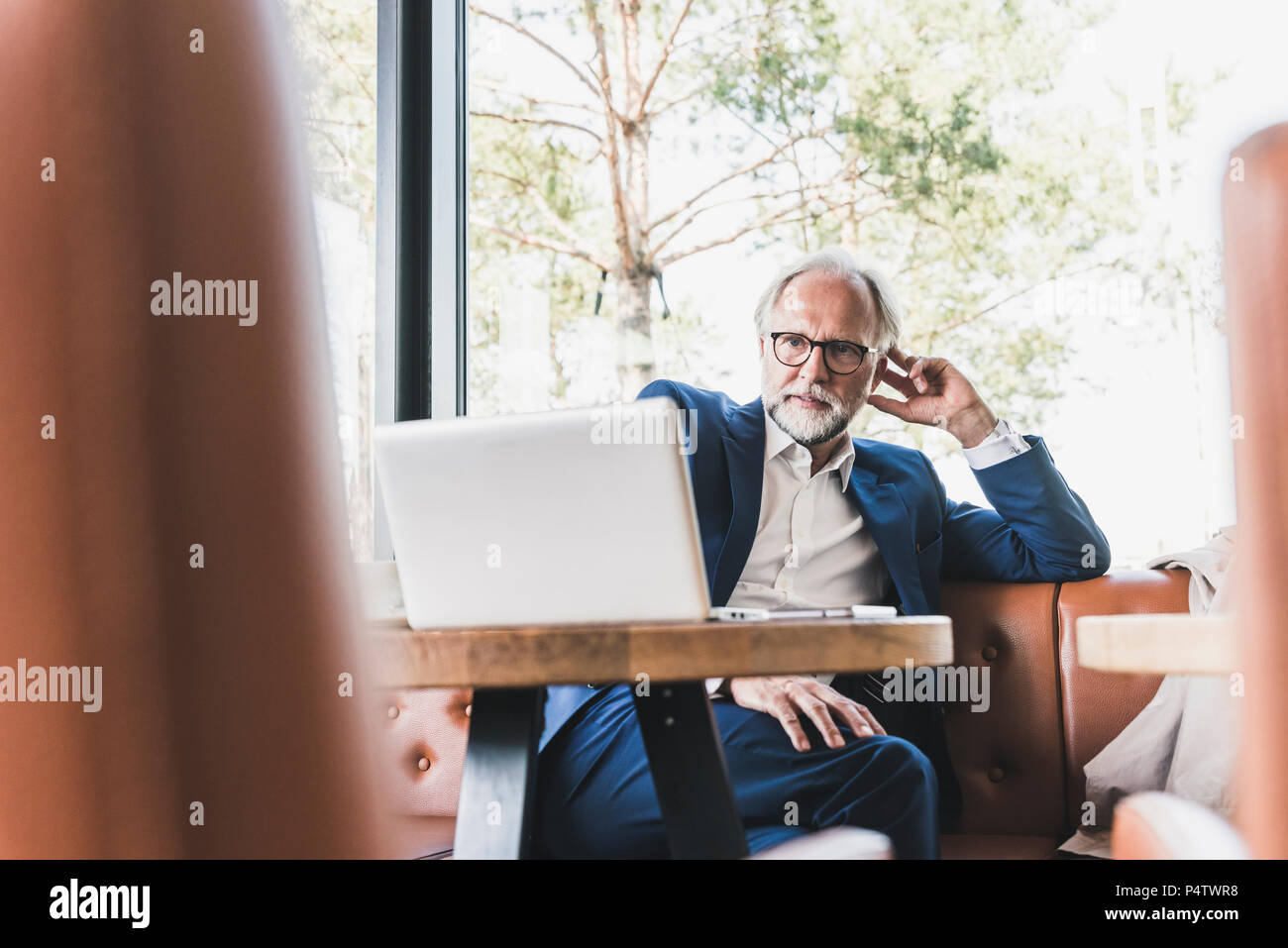 Mature businessman sitting at table in a cafe using laptop Stock Photo