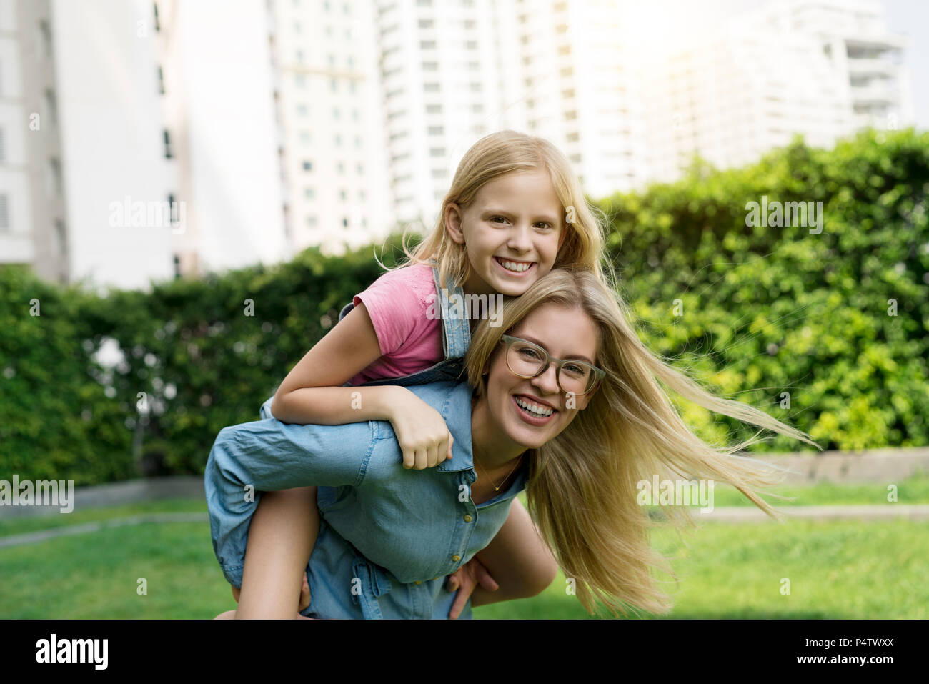 Portrait of happy mother and daughter in urban city garden Stock Photo