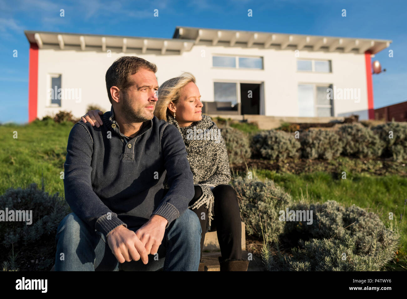 Couple sitting in the sun, in front of their house Stock Photo