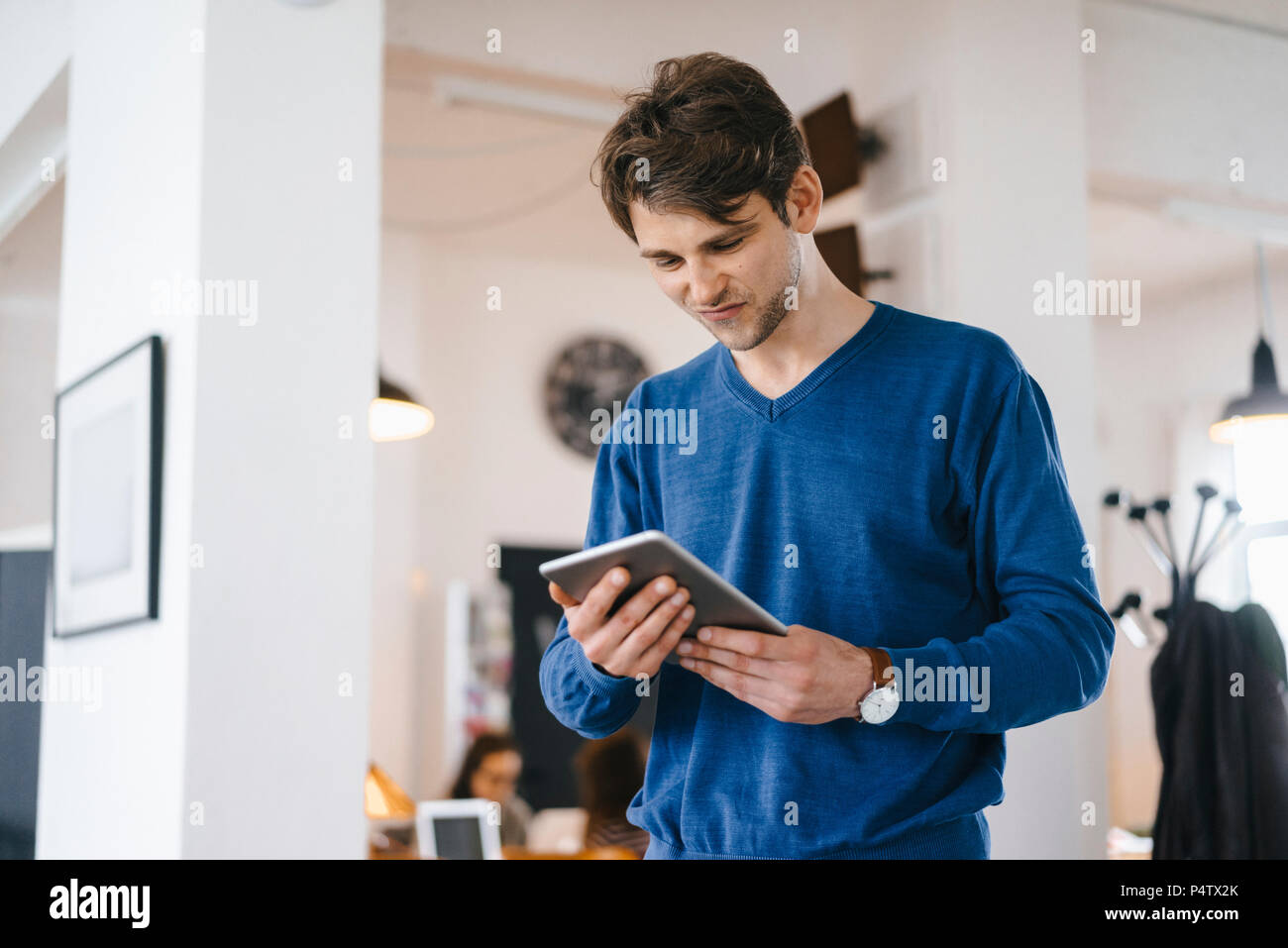 Man standing in a cafe looking at tablet Stock Photo