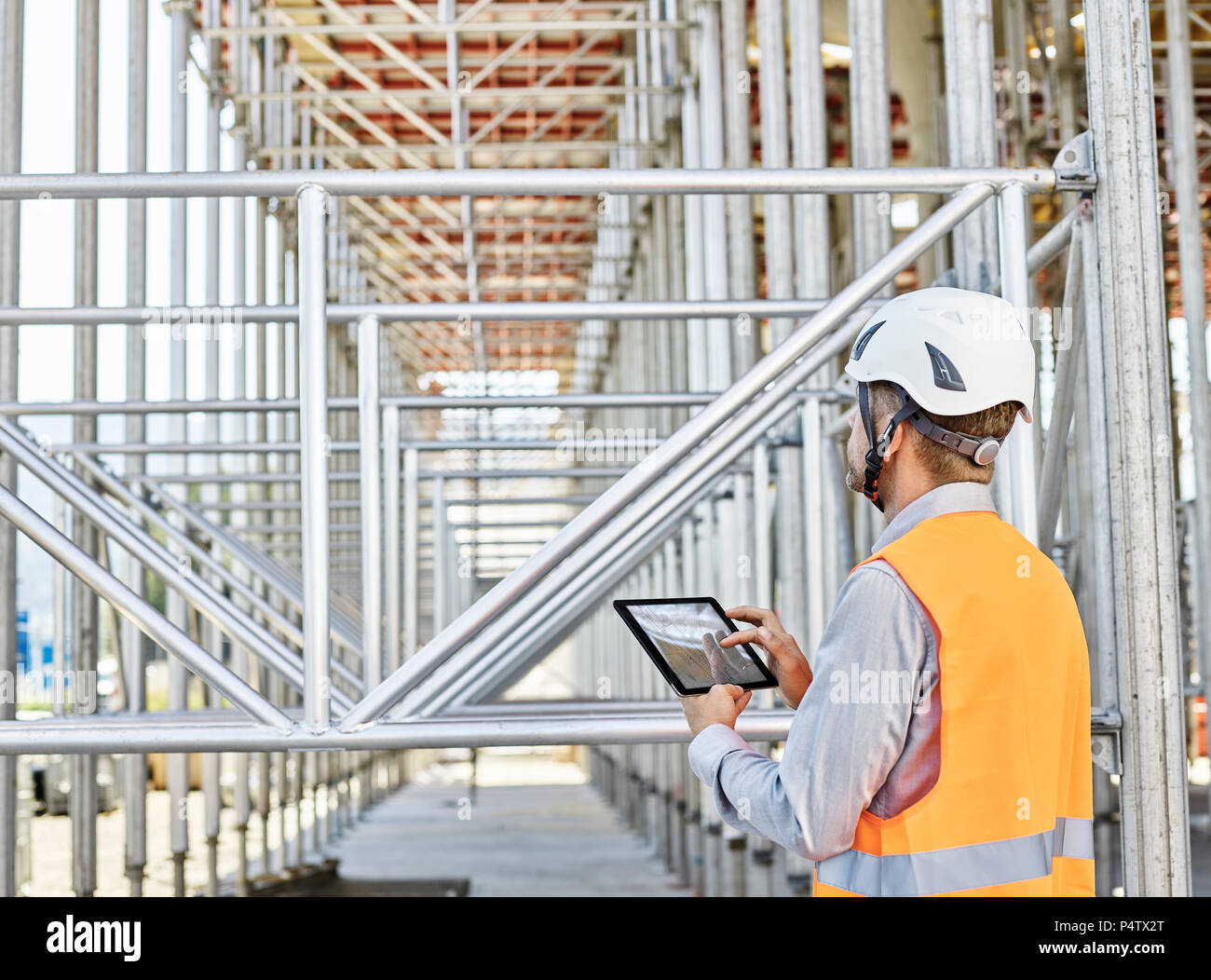 Architect with tablet wearing hard hat on construction site Stock Photo