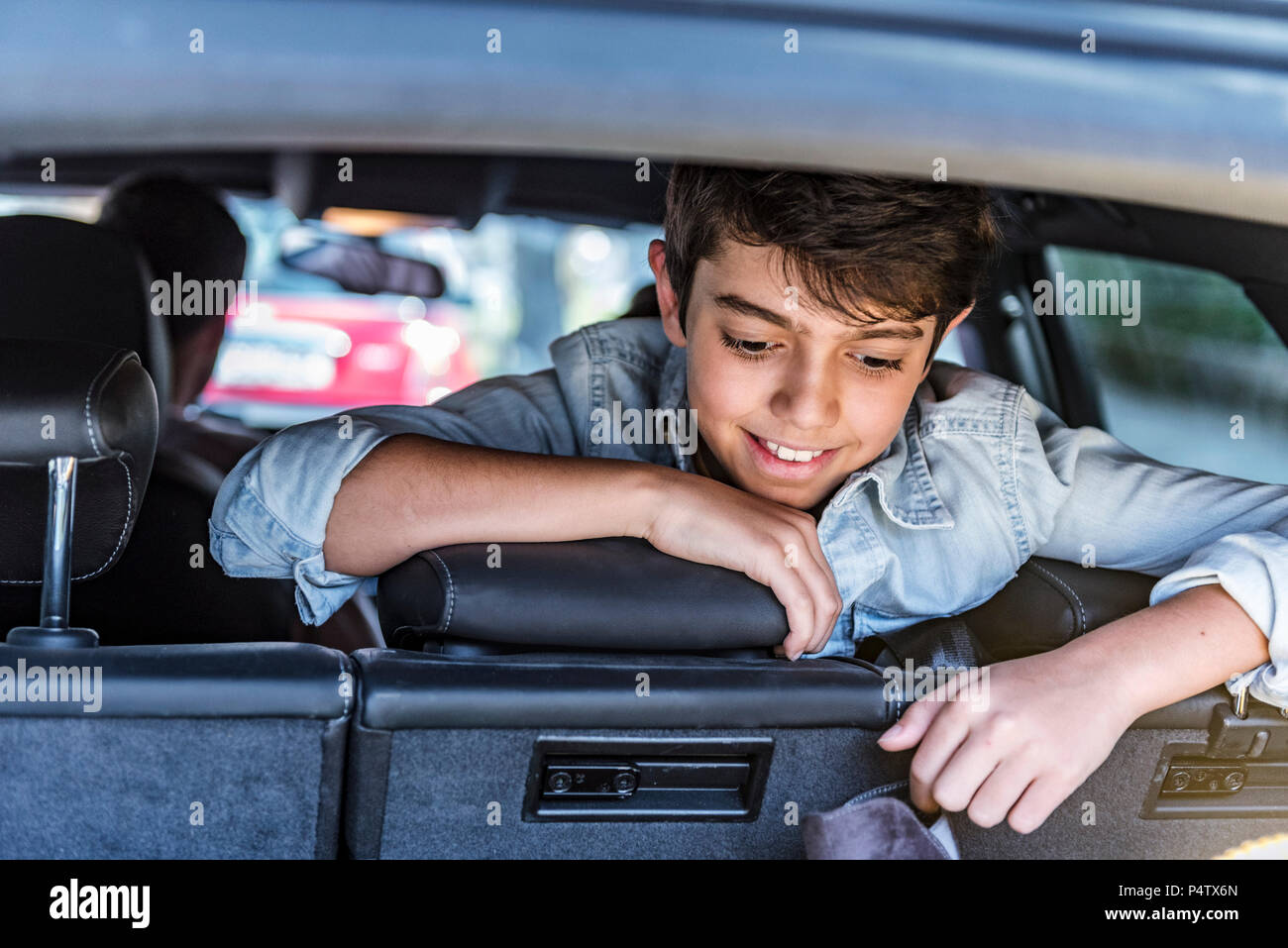 Smiling boy in car looking in boot Stock Photo
