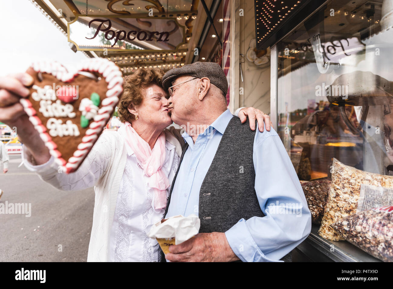 Senior couple with gingerbread heart  kissing on fair Stock Photo