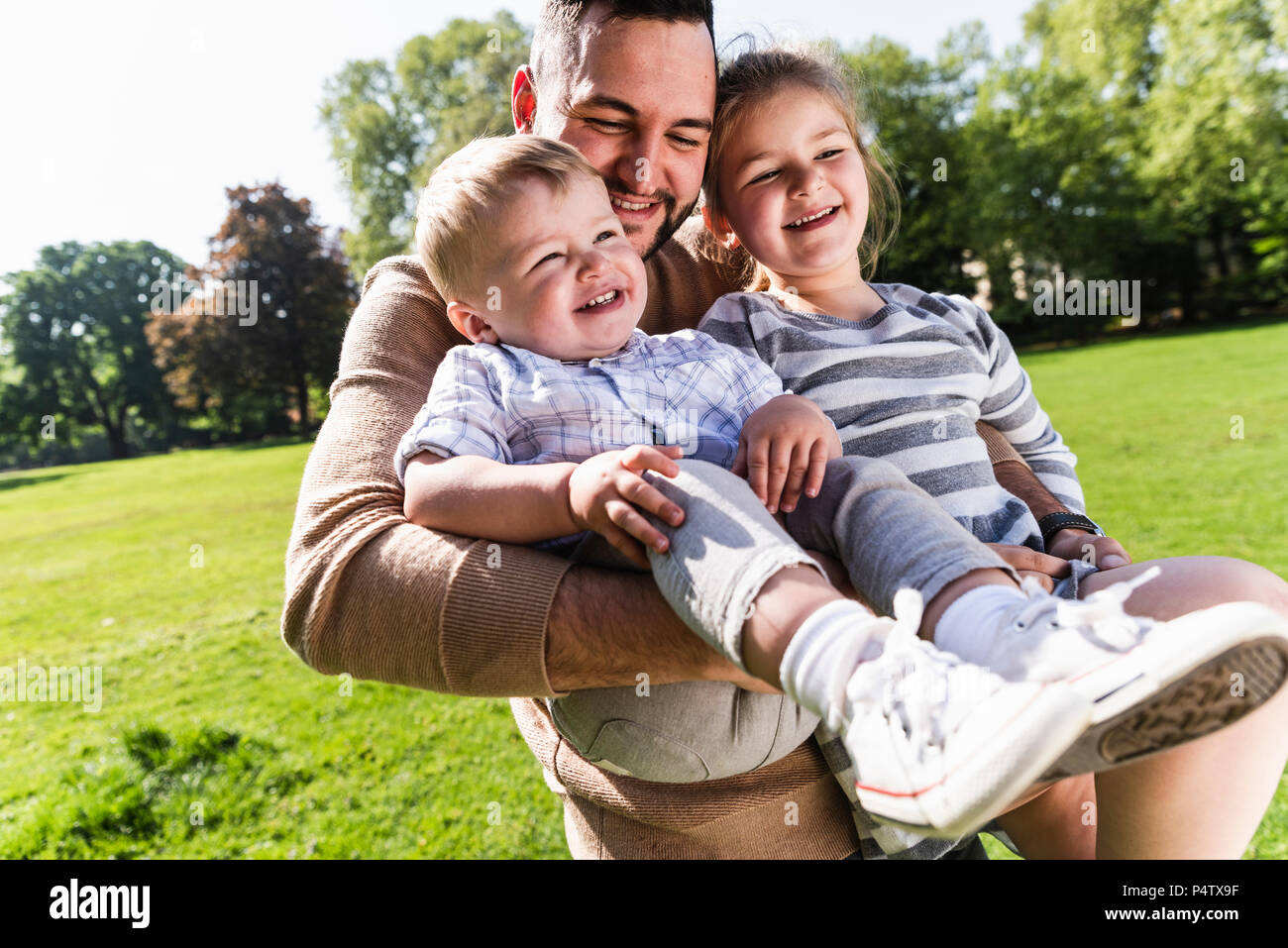 Happy father carrying children in a park Stock Photo - Alamy