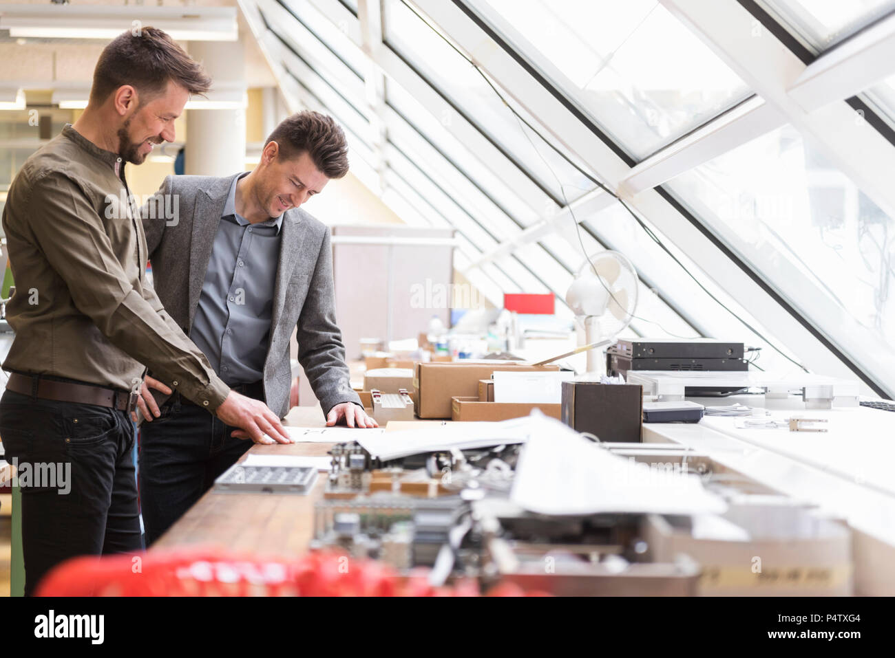 Two smiling businessmen looking at plan in factory Stock Photo - Alamy