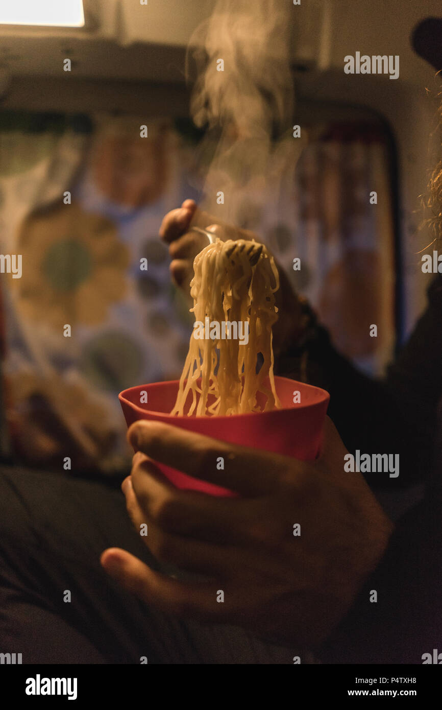 Man eating noodles in camper, close-up Stock Photo