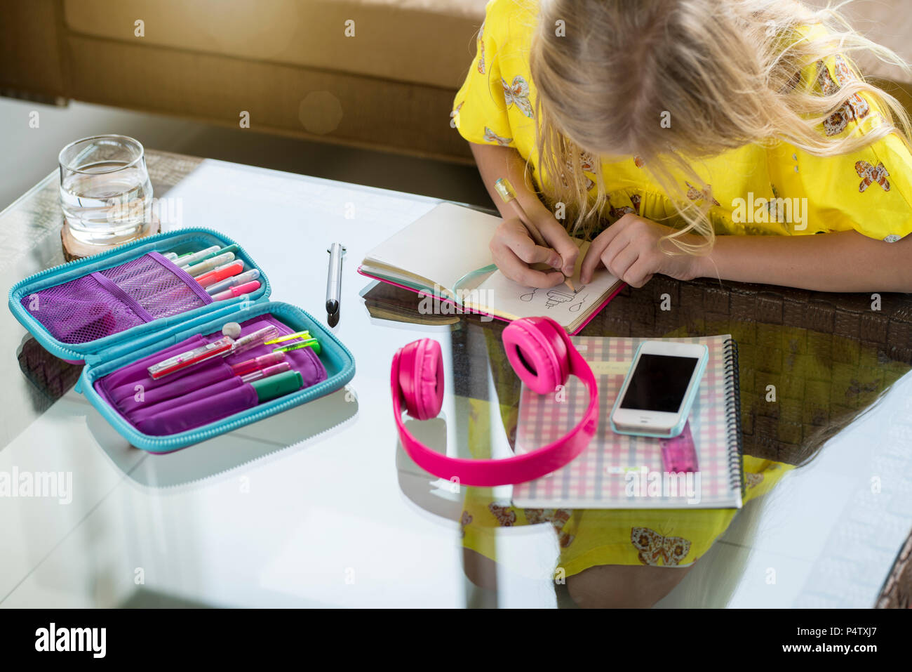 Girl doing her homework writing in booklet on table in living room Stock Photo