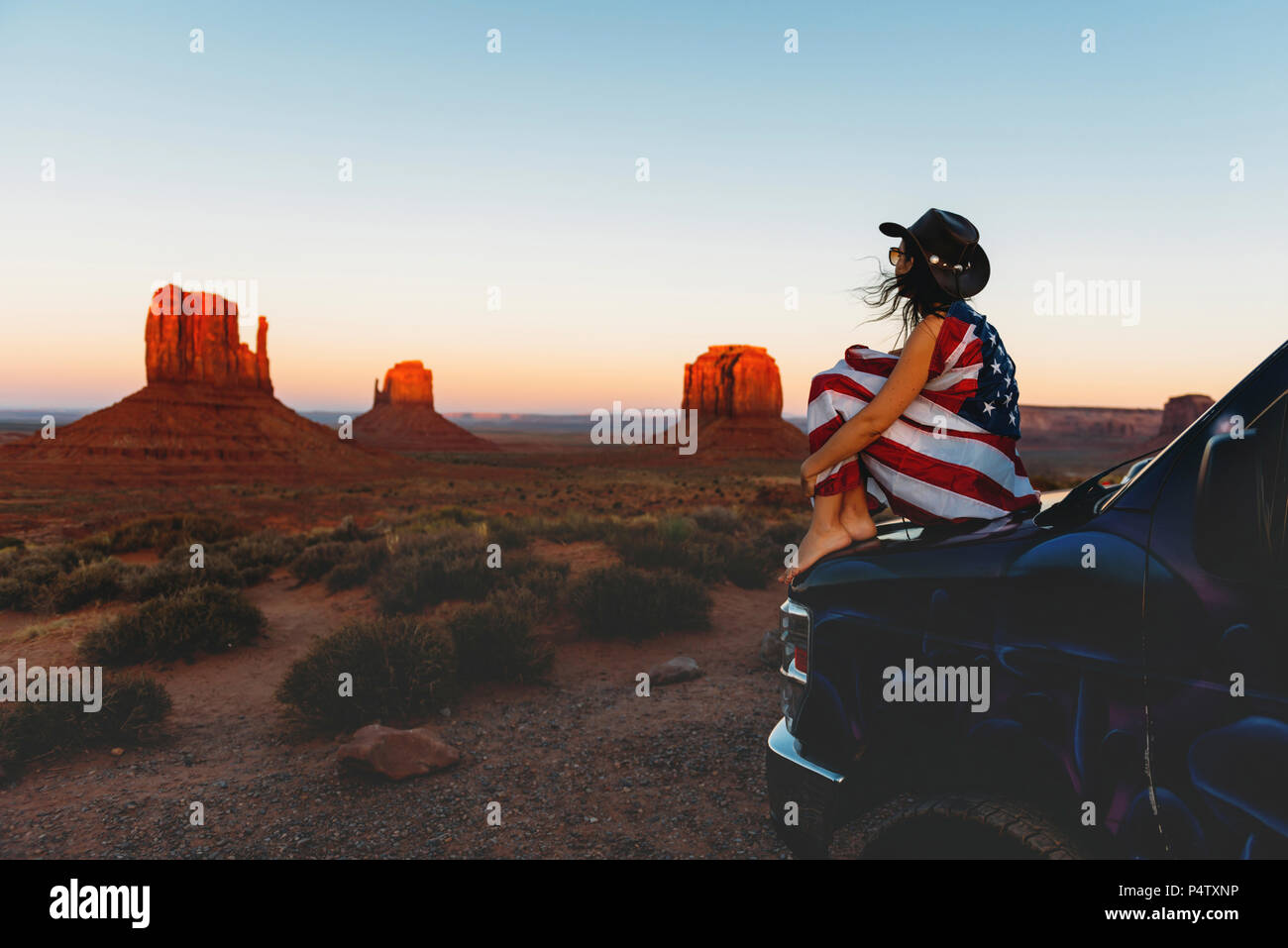 USA, Utah, Woman with United States of America flag enjoying the sunset in Monument Valley Stock Photo